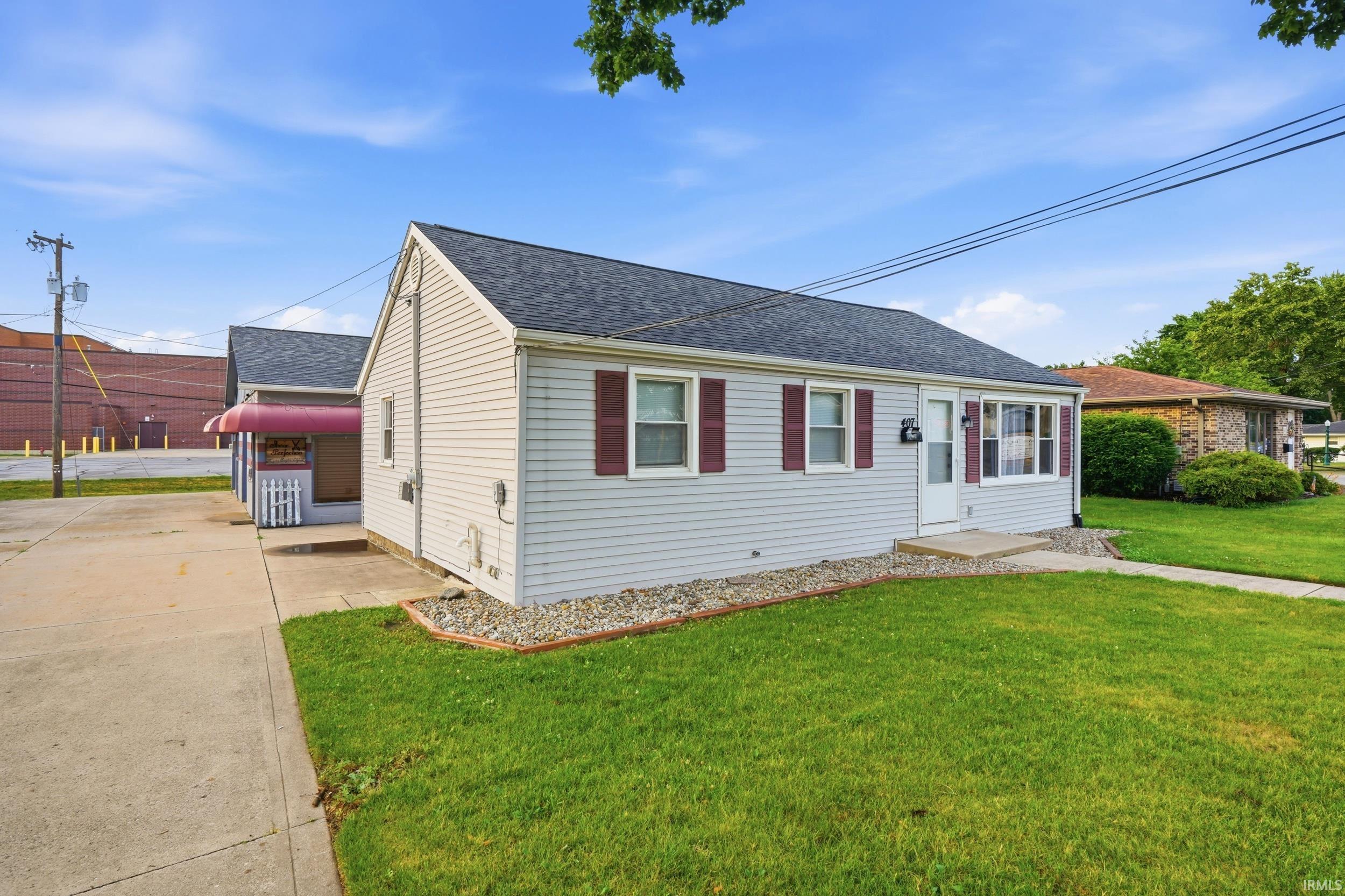 Ranch-style exterior featuring light-colored siding, a dark shingle roof, and contrasting red shutters