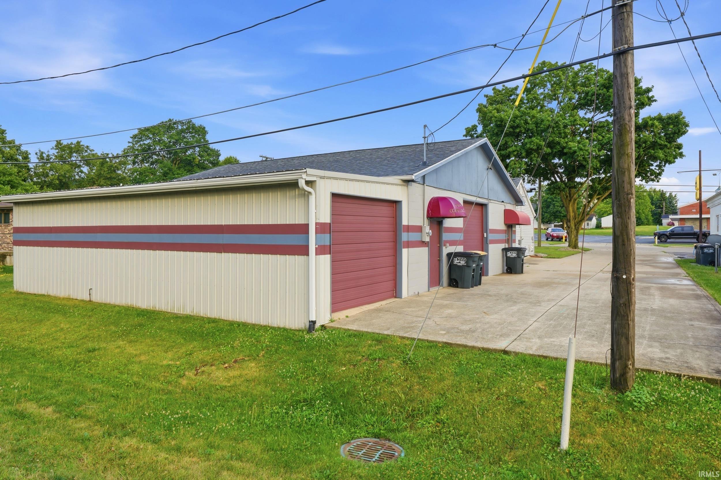 Commercial-style building featuring cream-colored corrugated metal siding with red and gray stripe accents
