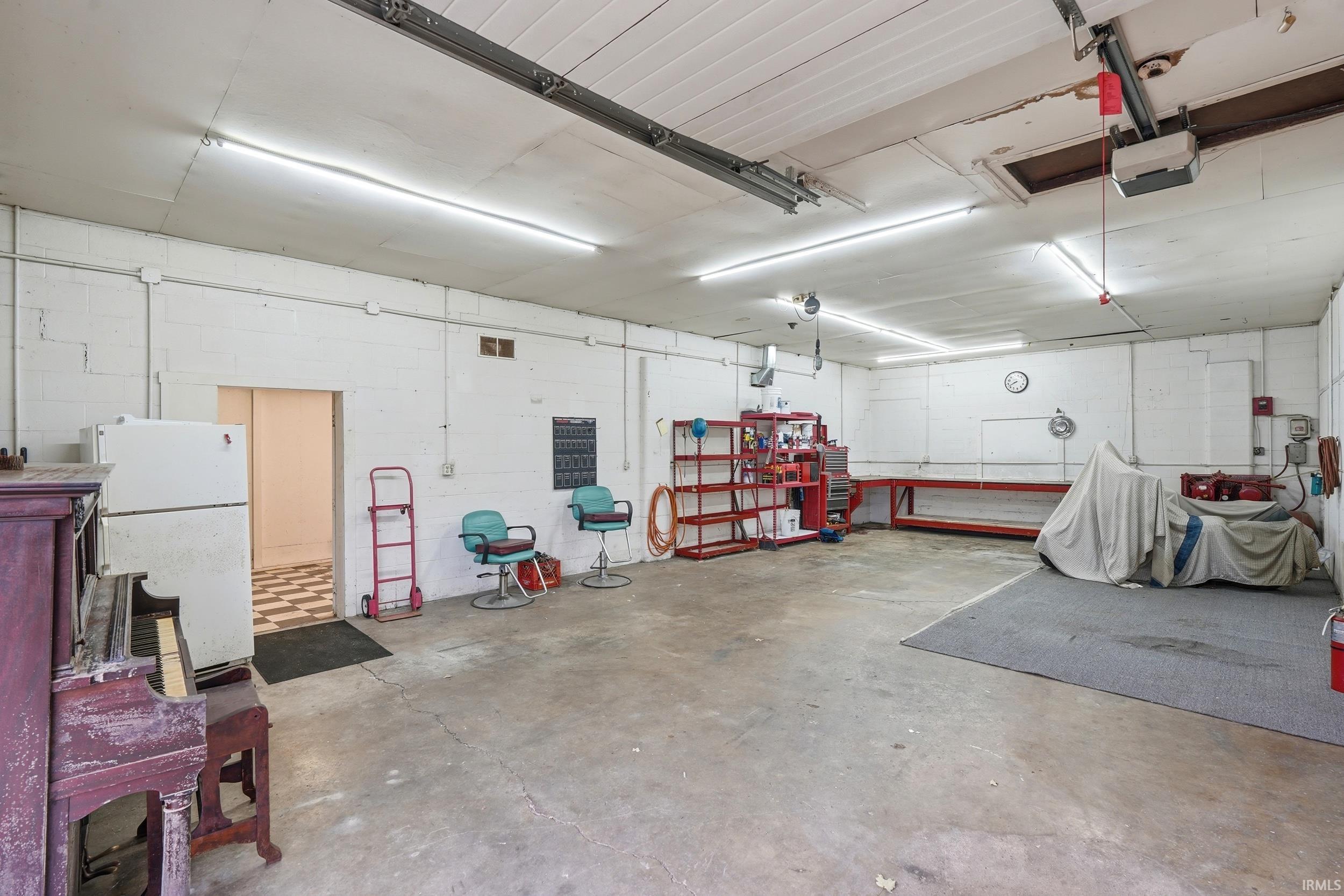 Spacious garage featuring a concrete floor, painted block walls, and fluorescent strip lighting