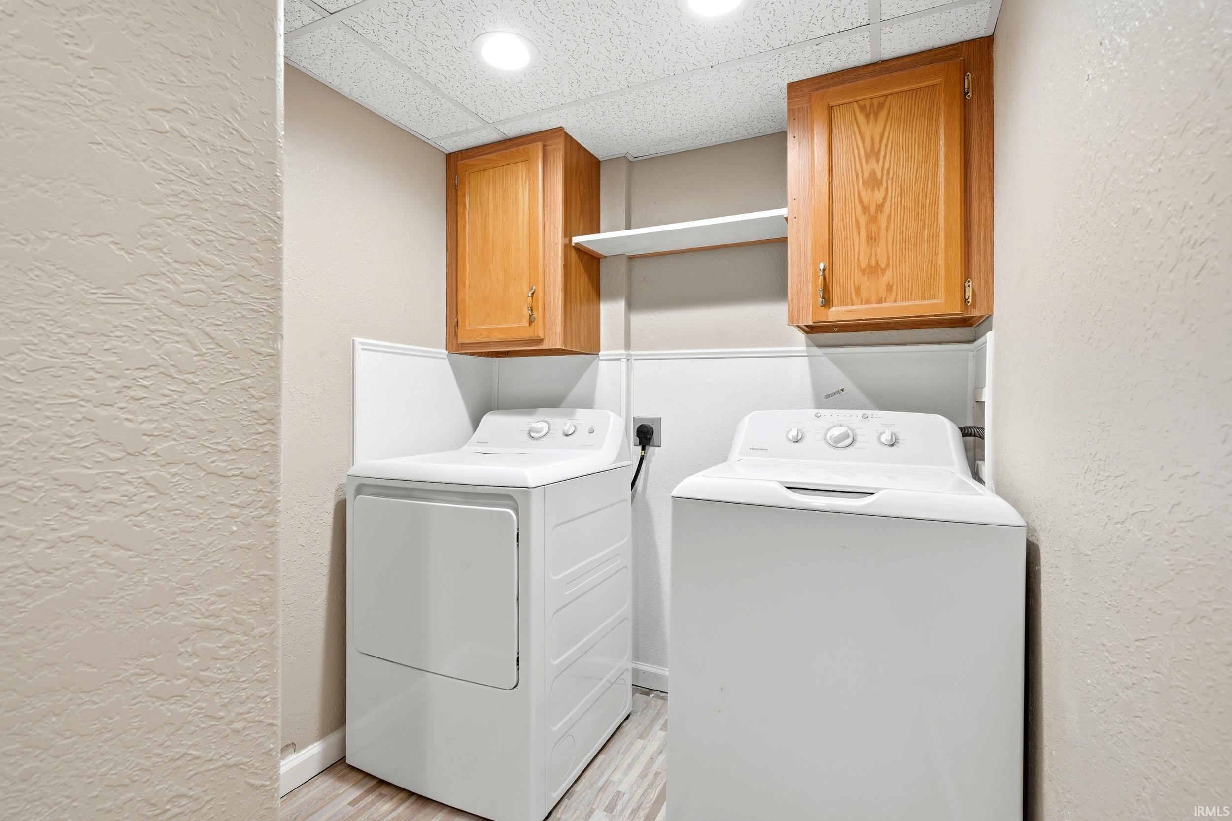 Dedicated laundry area featuring a washer and dryer, wood-finish cabinetry, a utility shelf, and recessed ceiling lighting