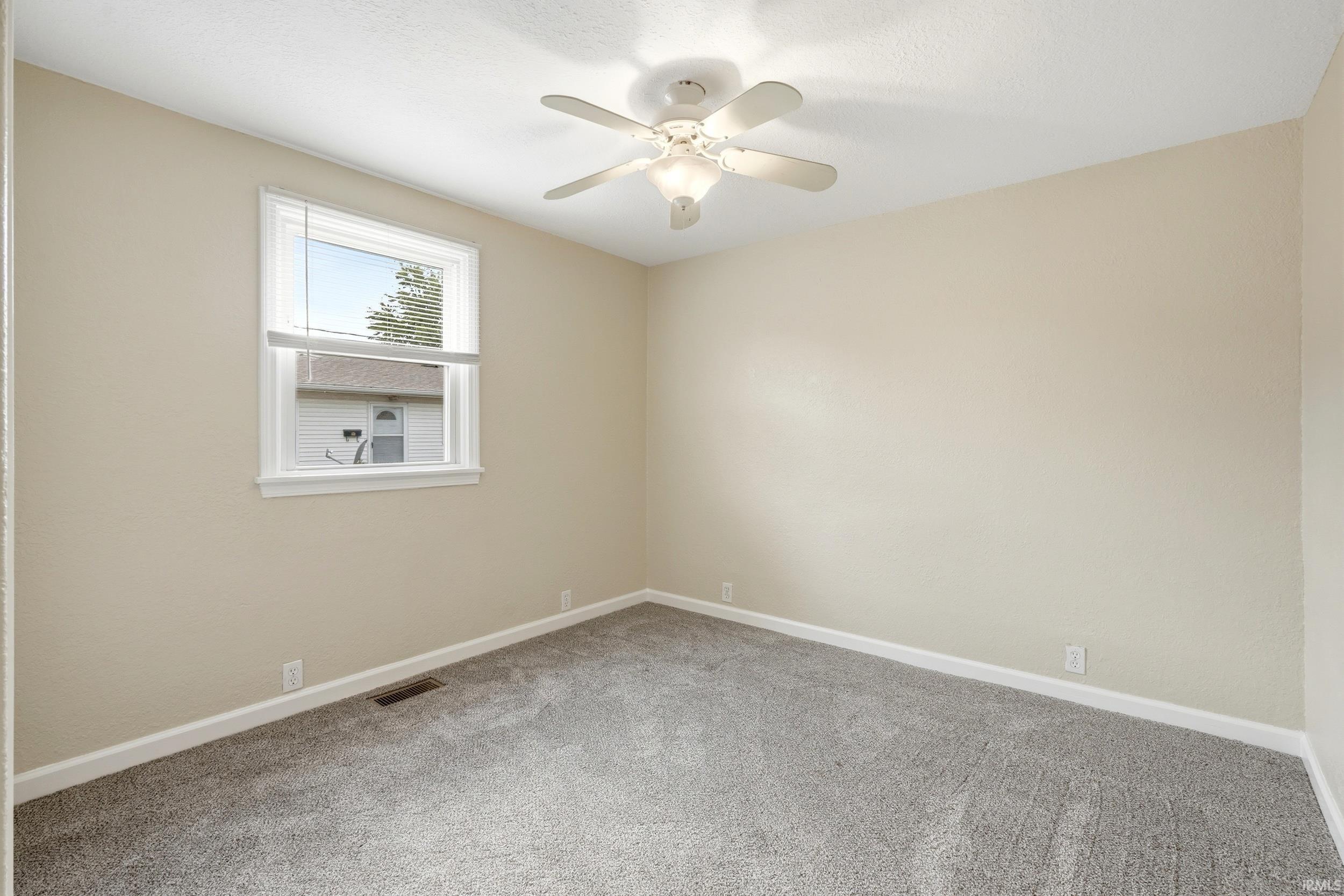 Interior room featuring light beige walls, gray carpeting, and white baseboards