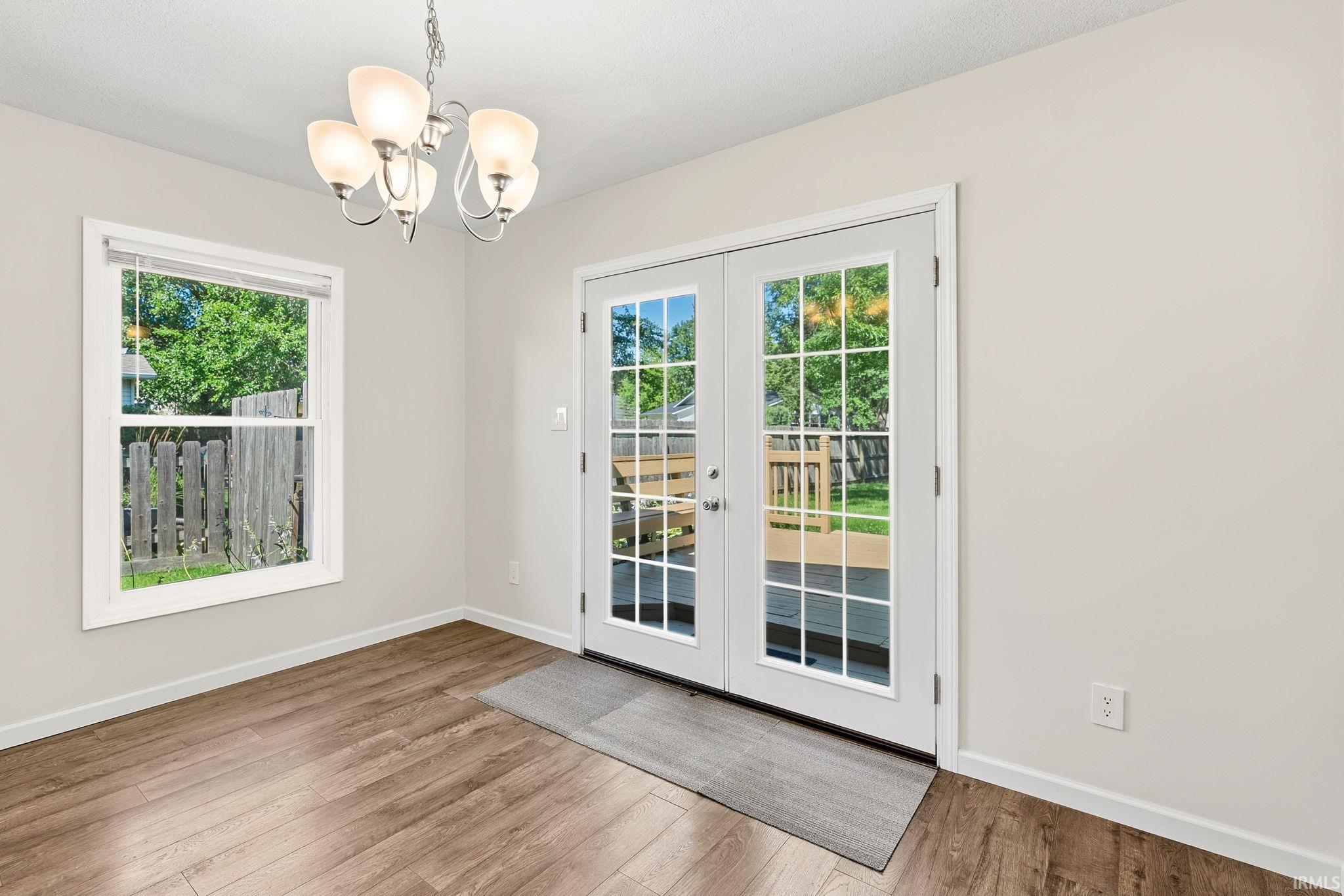 Room featuring wood-finish flooring, a white window, and French doors with grid-patterned glass