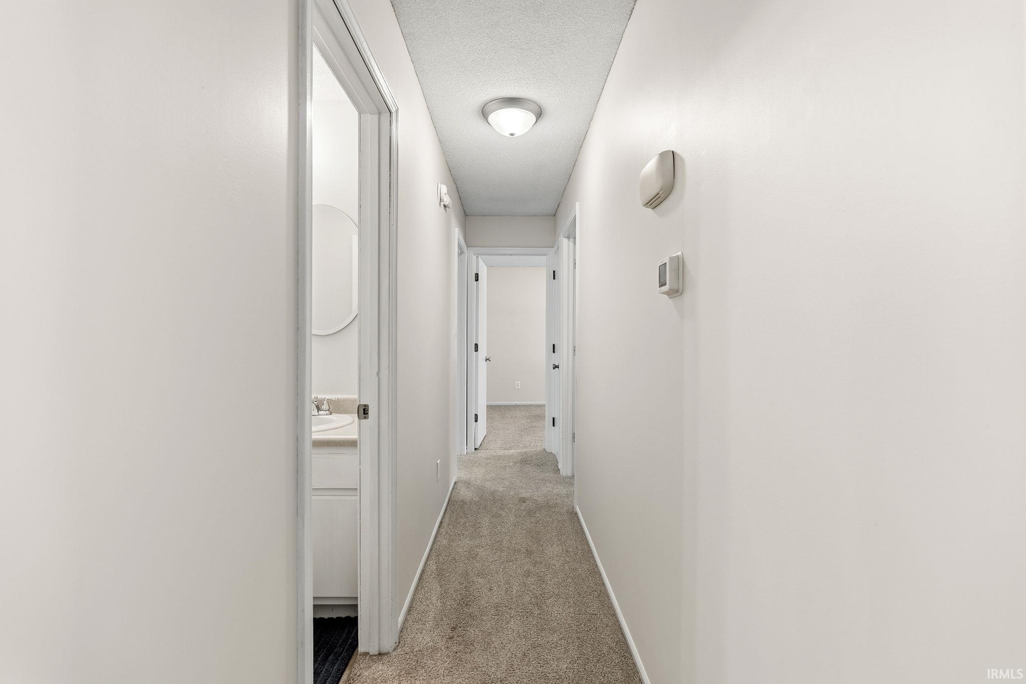Hallway featuring light gray walls and carpeting