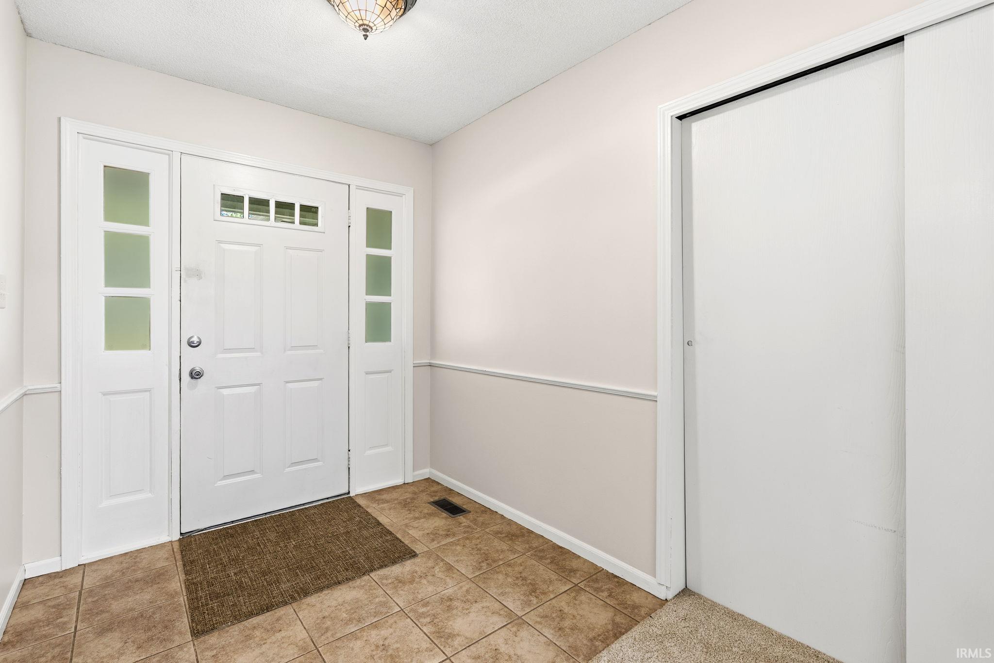 Entryway featuring a white paneled door with glass inserts, flanked by matching sidelights and a transom window