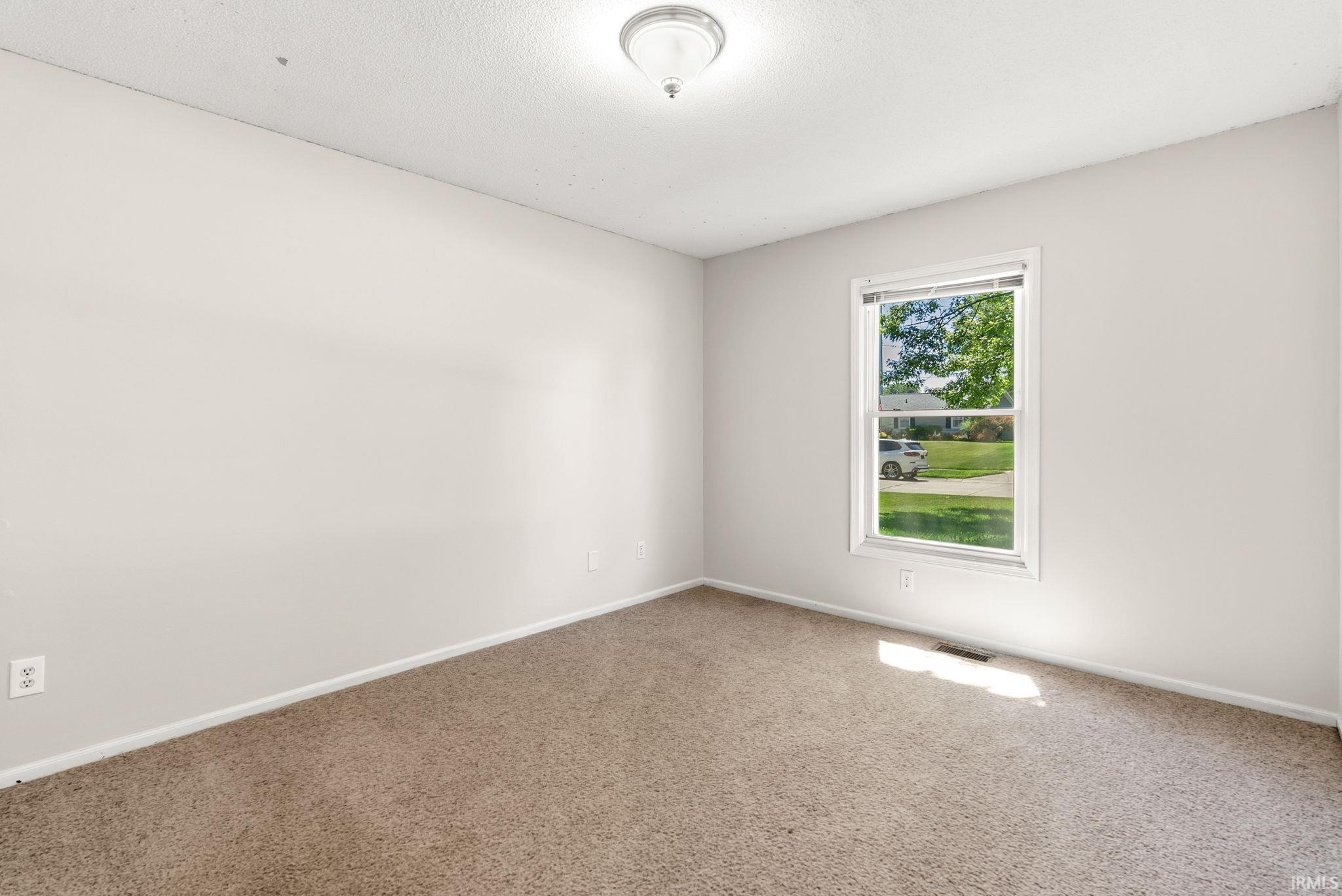 Carpeted room with neutral wall tones and a single window