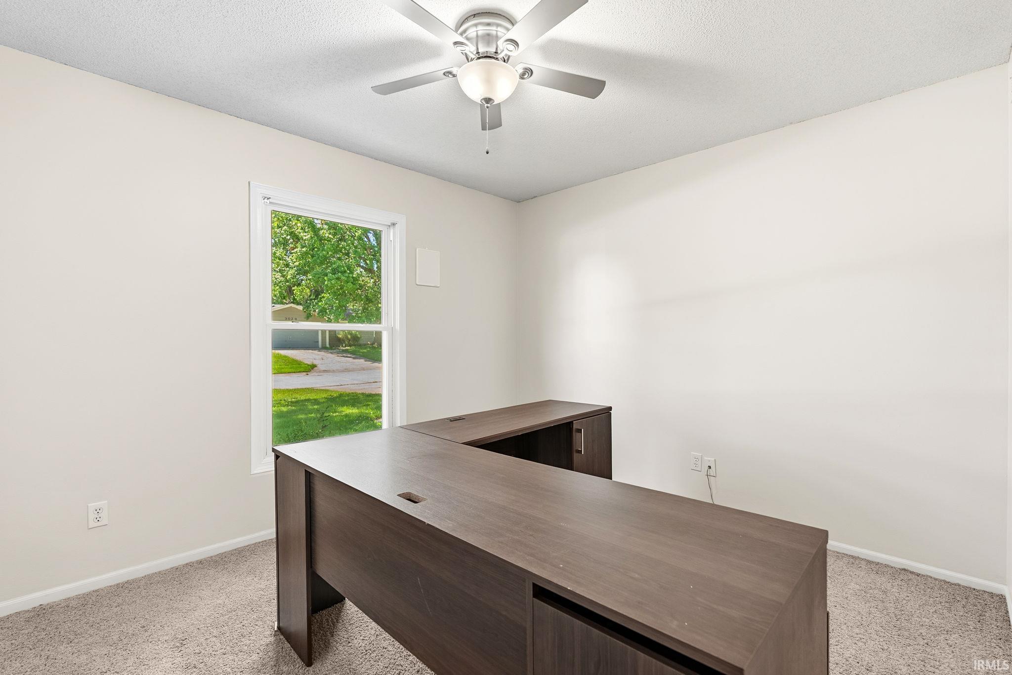 Interior room featuring neutral wall paint, light-colored carpet, and a ceiling fan with integrated lighting