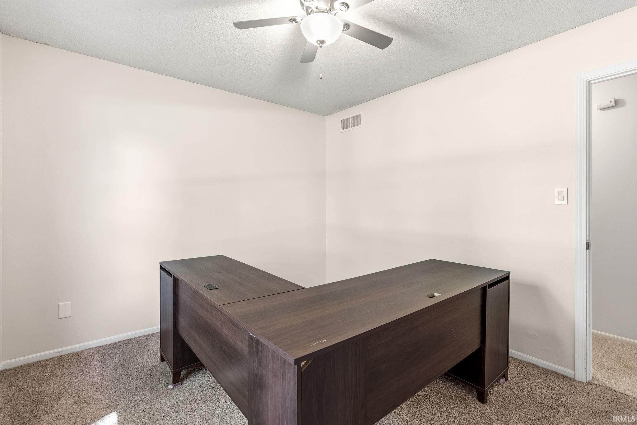 Room with light neutral walls, carpet flooring, a ceiling fan with integrated lighting, and white baseboards