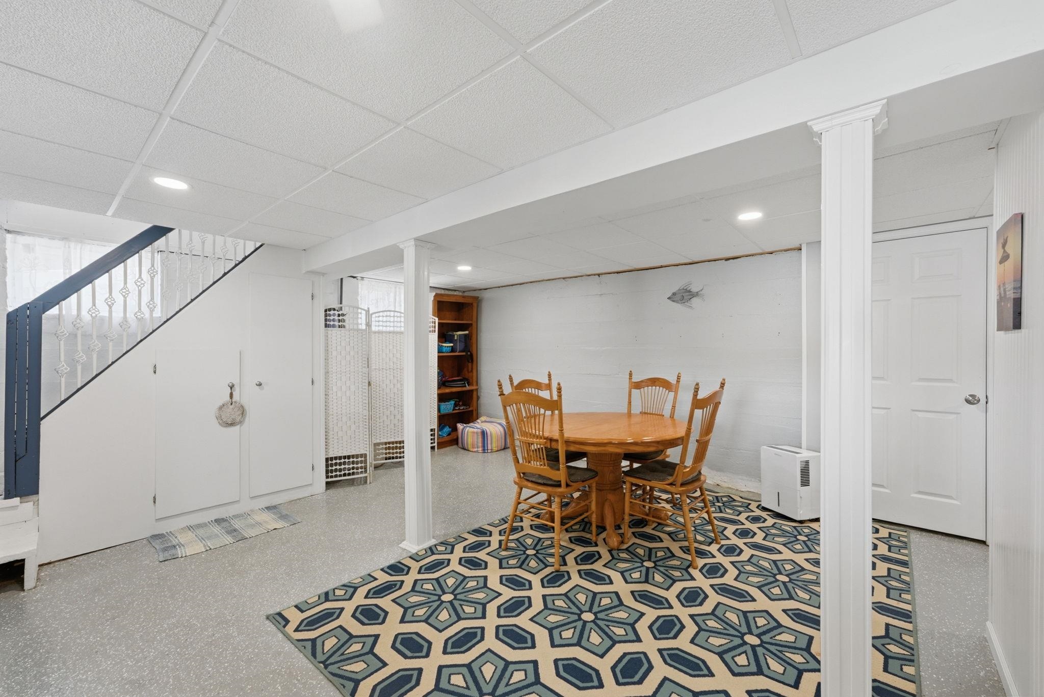 Finished lower-level space featuring recessed lighting, paneled ceiling, painted support columns, and an enclosed staircase with built-in storage Walk out to covered porch, deck and sprawling lakefront lot