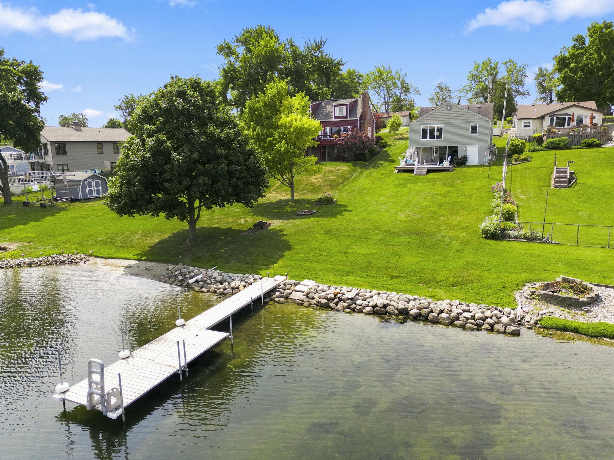 Waterfront property featuring a private dock w ladder, rocky shoreline, walkin clean beach, and an outdoor fire pit