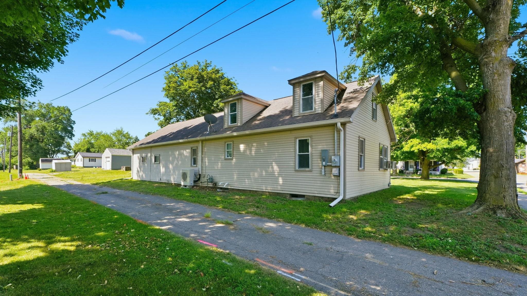 Side profile of a two-story residence featuring light-colored siding and a gabled roofline with two dormer windows