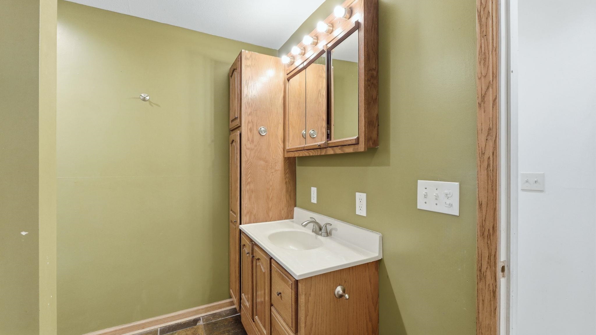 Bathroom vanity with an integrated sink, light wood-finish cabinetry, and a white countertop