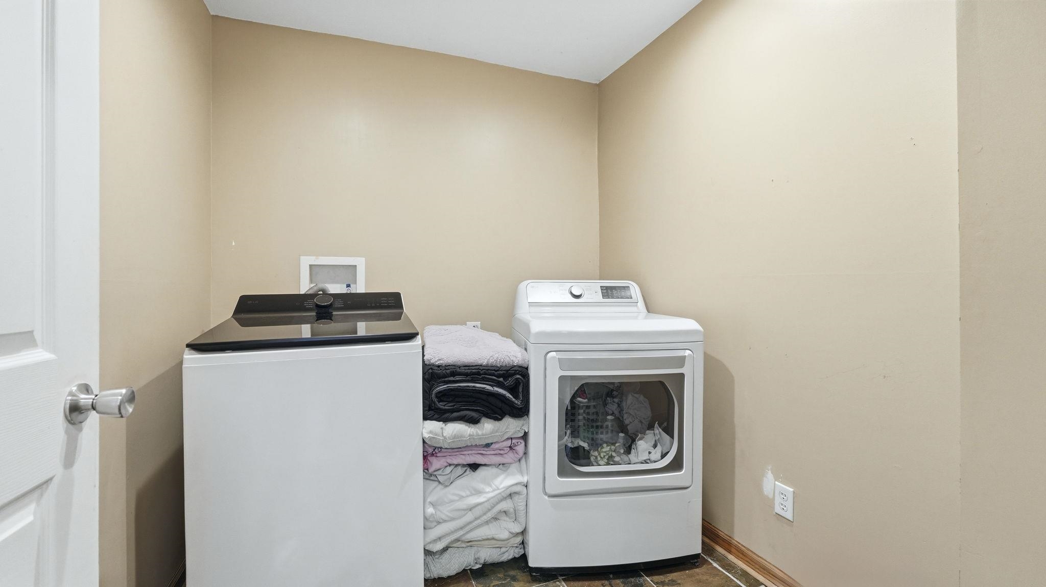 Dedicated laundry room featuring light beige walls and dark wood-finish flooring