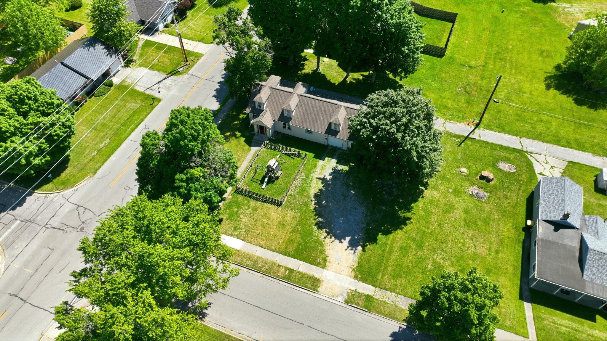 Aerial perspective showcasing a property with a light-toned exterior and a gray shingled roof