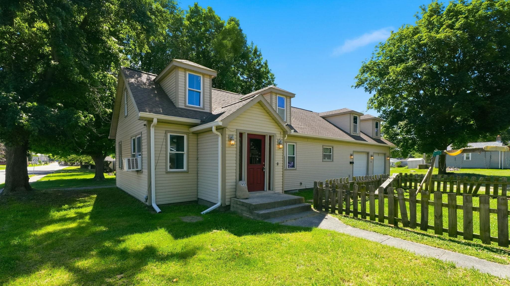 Siding-clad home featuring a red entry door, two dormer windows, and an attached two-car garage