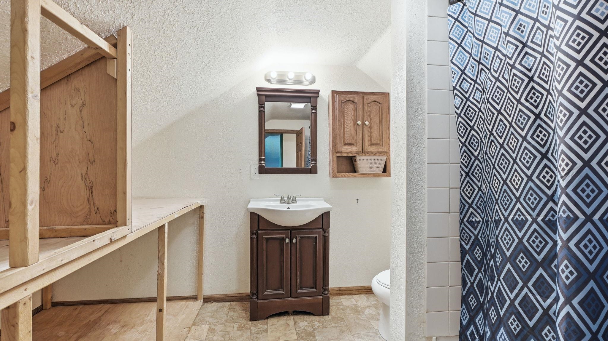 Bathroom featuring a dark wood-finish vanity with an integrated sink, a matching wall-mounted mirror, and a coordinating wood-finish wall cabinet
