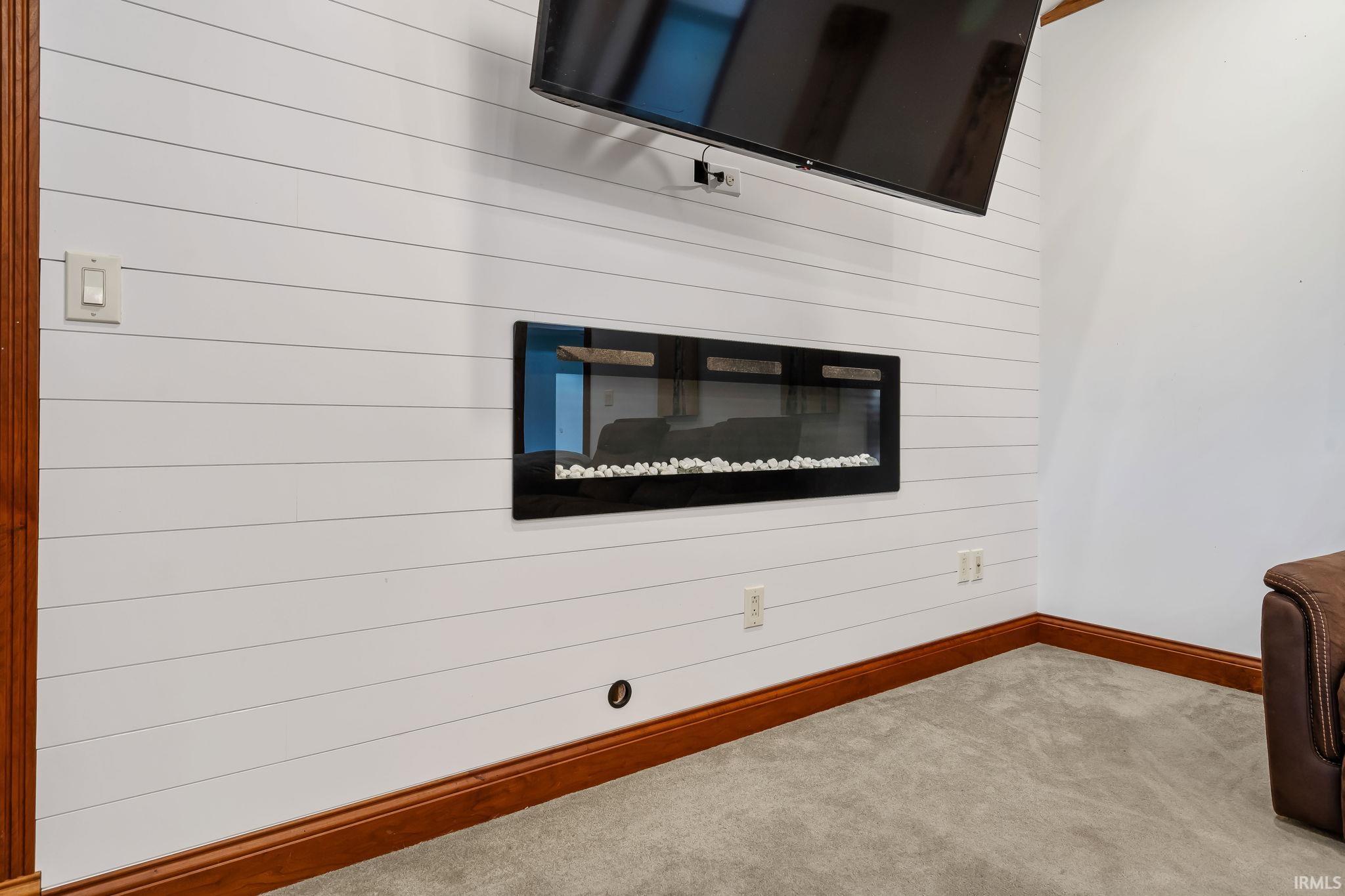 Shiplap accent wall featuring an inset electric fireplace with a glass front and white stone media