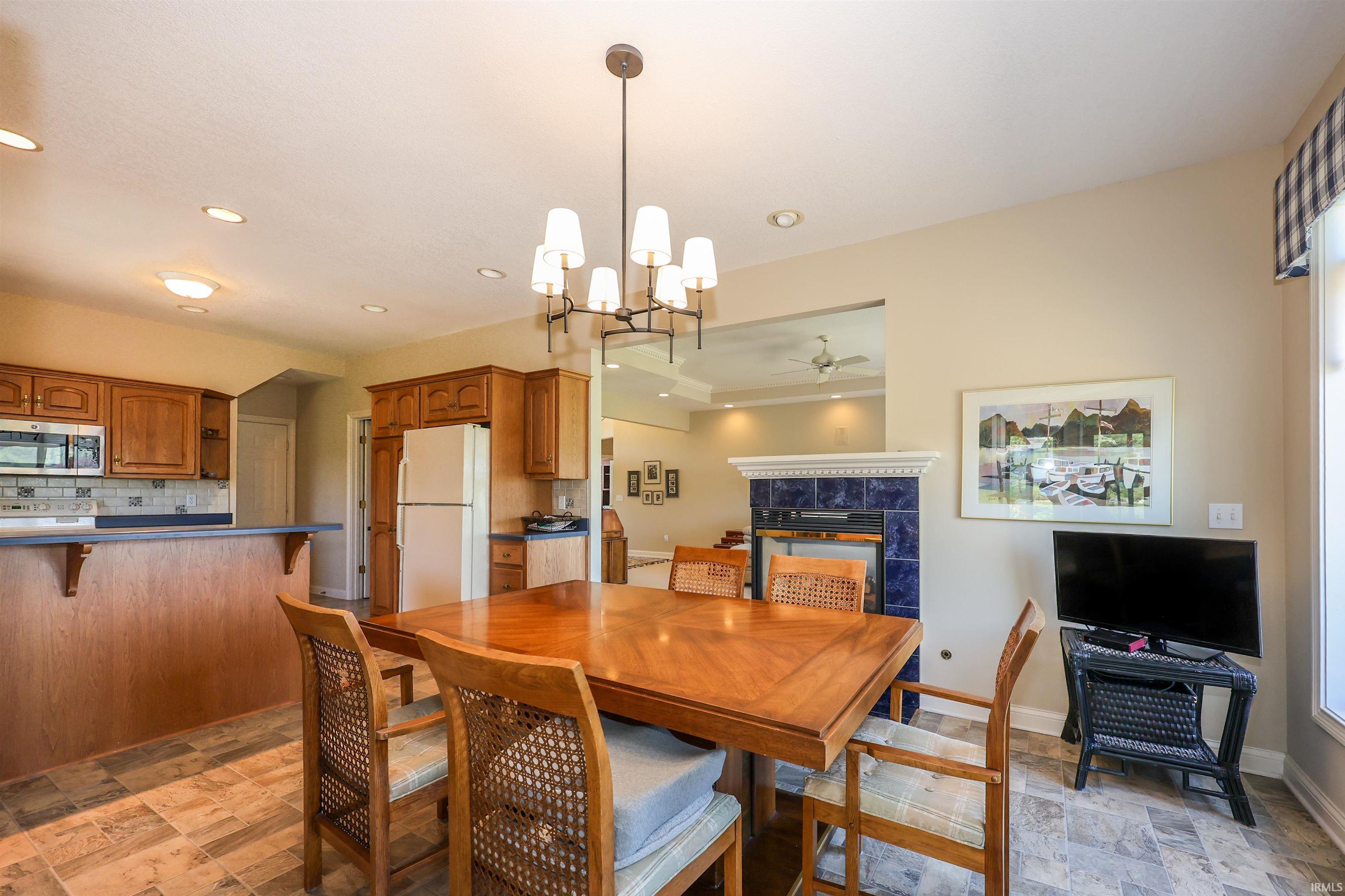 Dining area featuring a contemporary chandelier, tile flooring, and an open layout to the kitchen