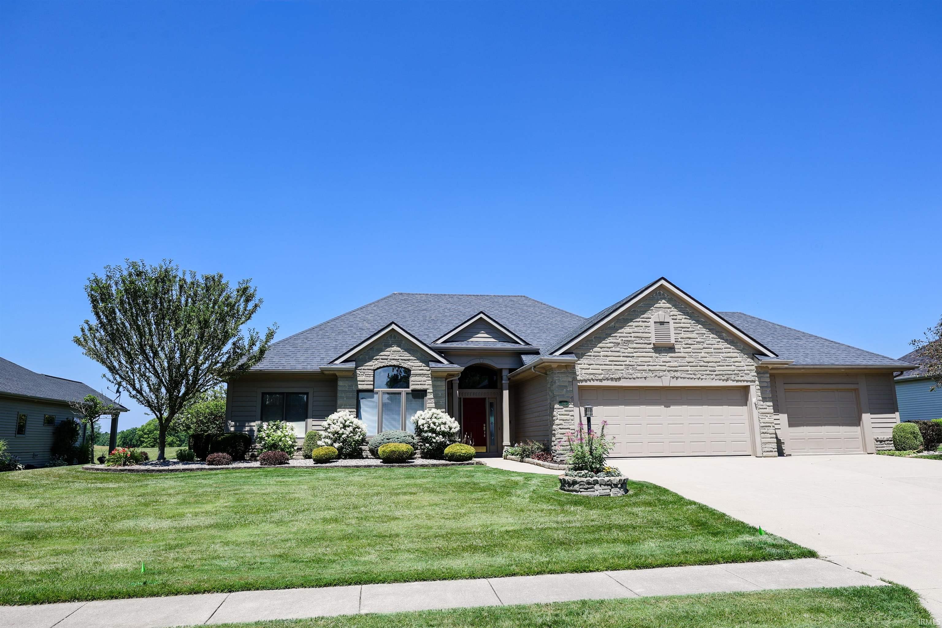 Stone and siding facade residence with a multi-gabled roofline, featuring an arched entry, a two-car garage, and a single-car garage