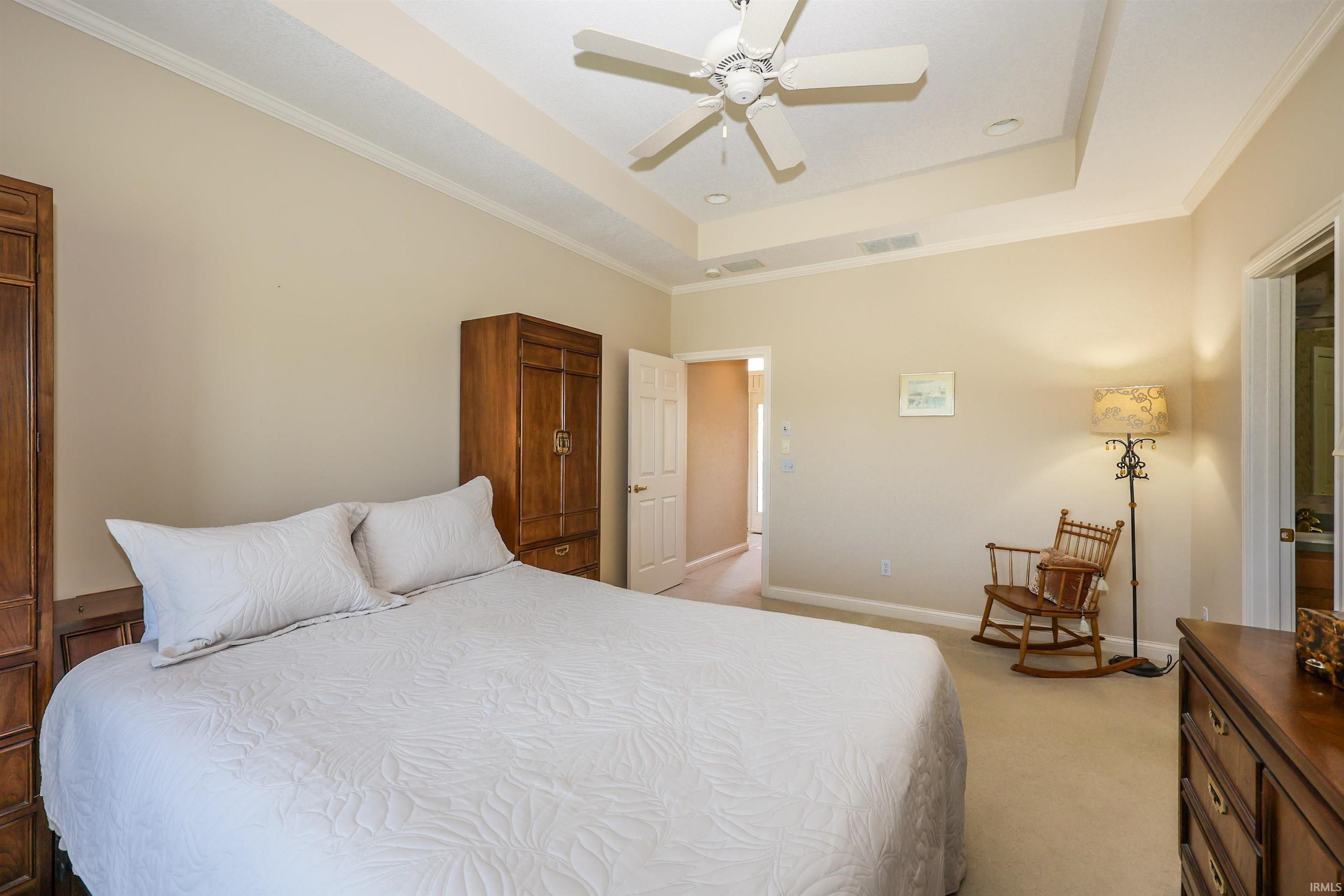 Recessed ceiling with a central fan light fixture, crown molding, and neutral wall tones
