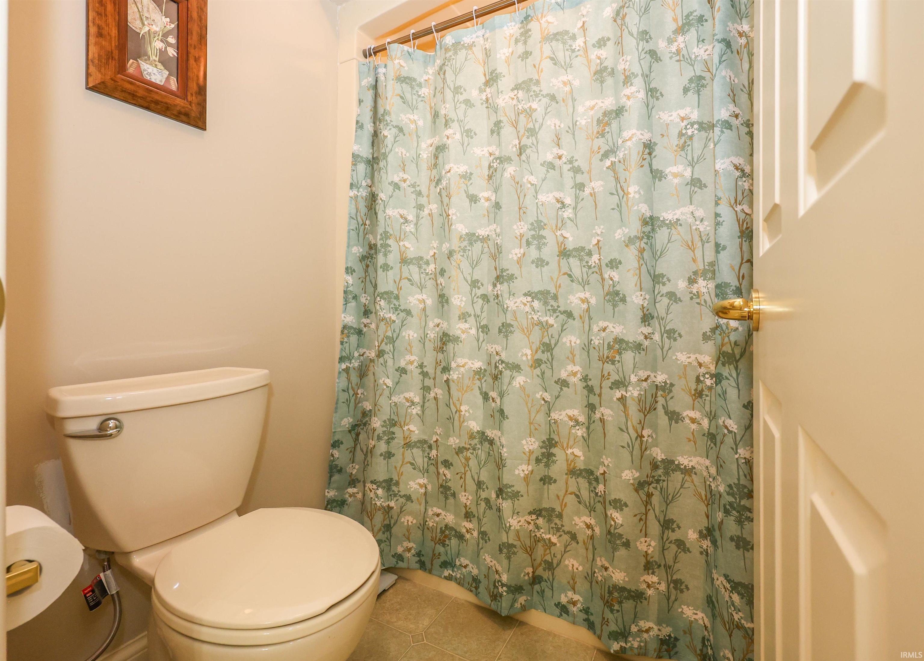 Bathroom featuring a white toilet, light-colored walls, and a paneled door with a brass doorknob