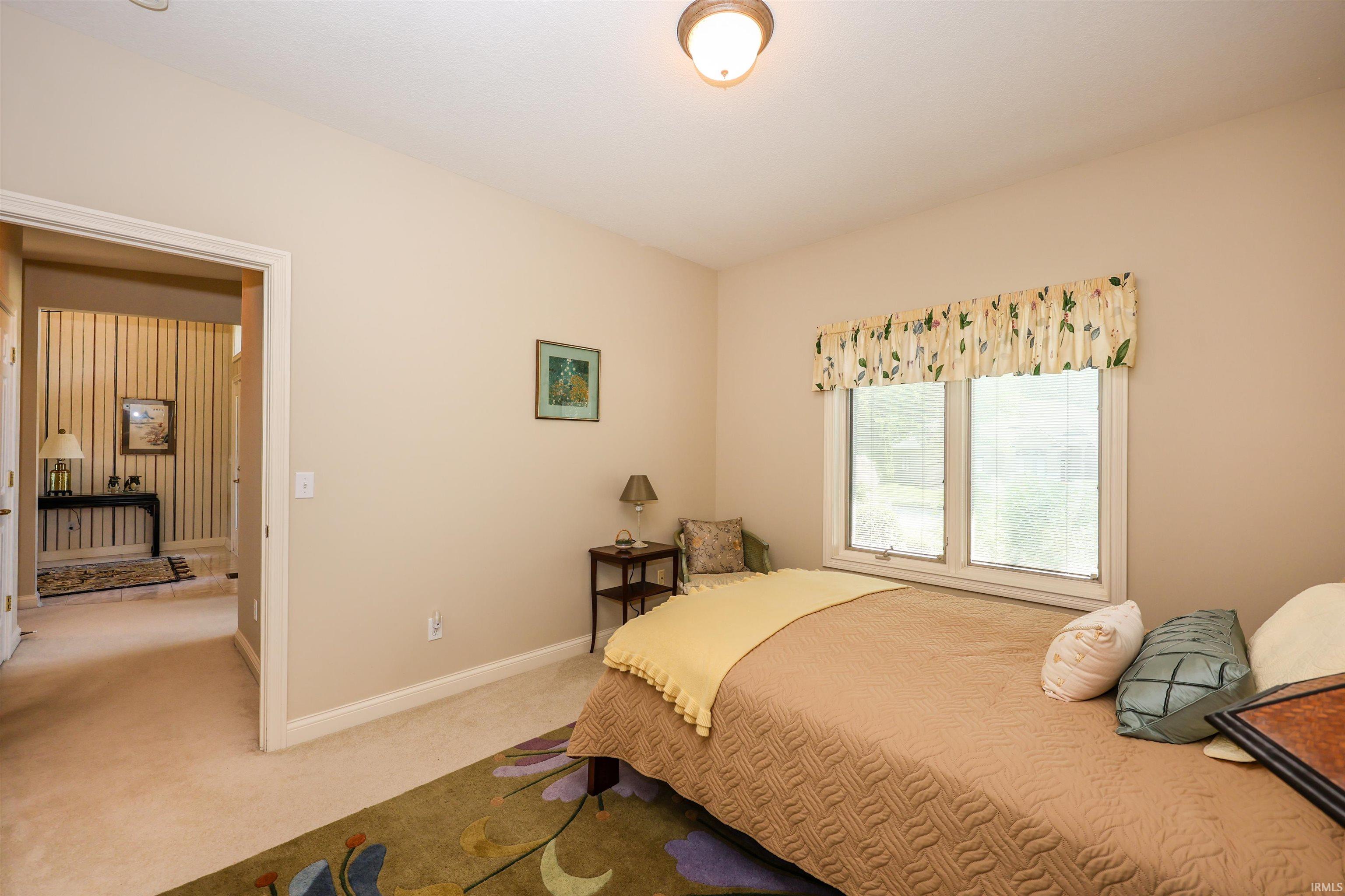 Bedroom featuring neutral wall paint, light-colored carpeting, a double window, and a flush-mount ceiling light