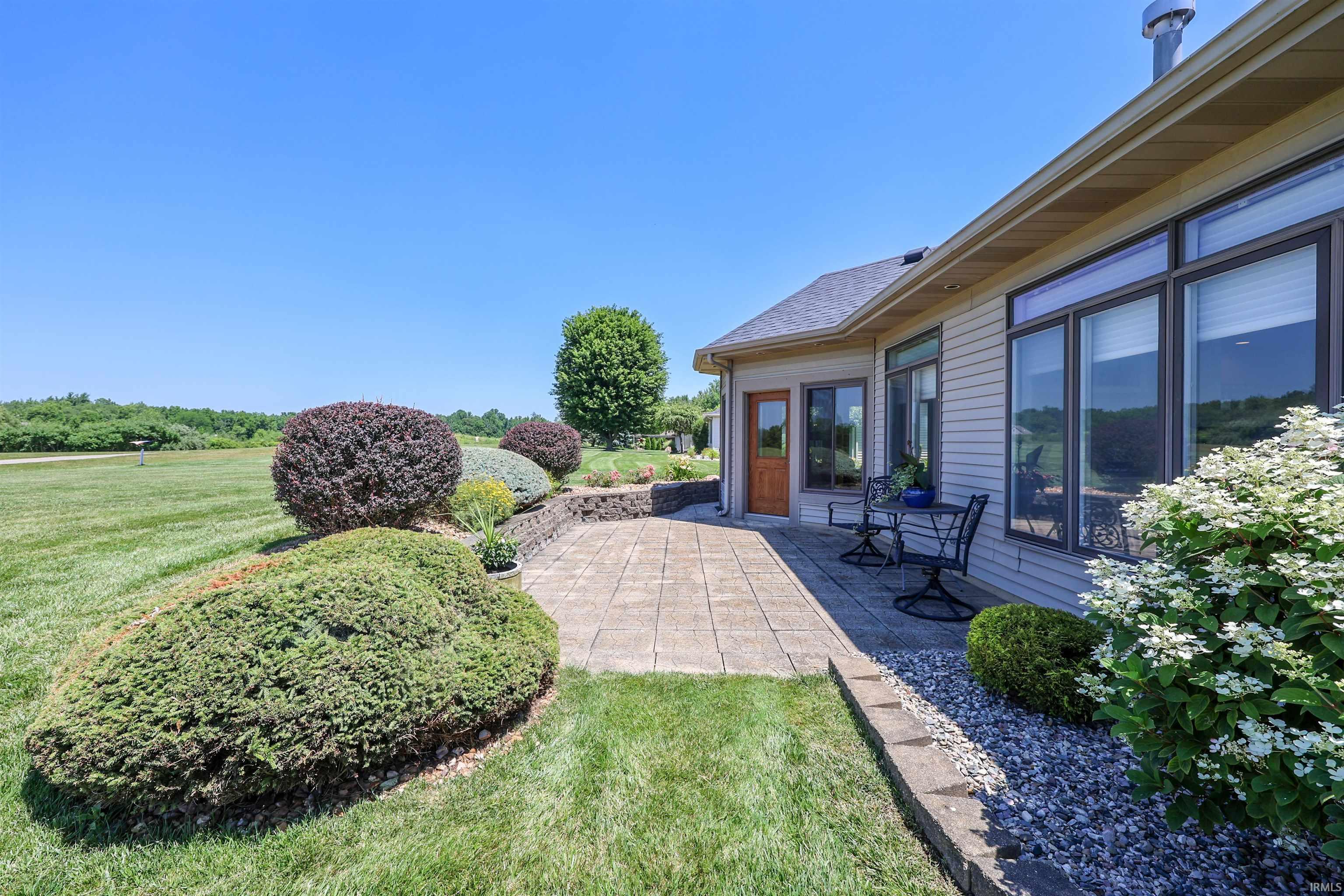 Expansive paver patio bordered by landscaping and a stone retaining wall