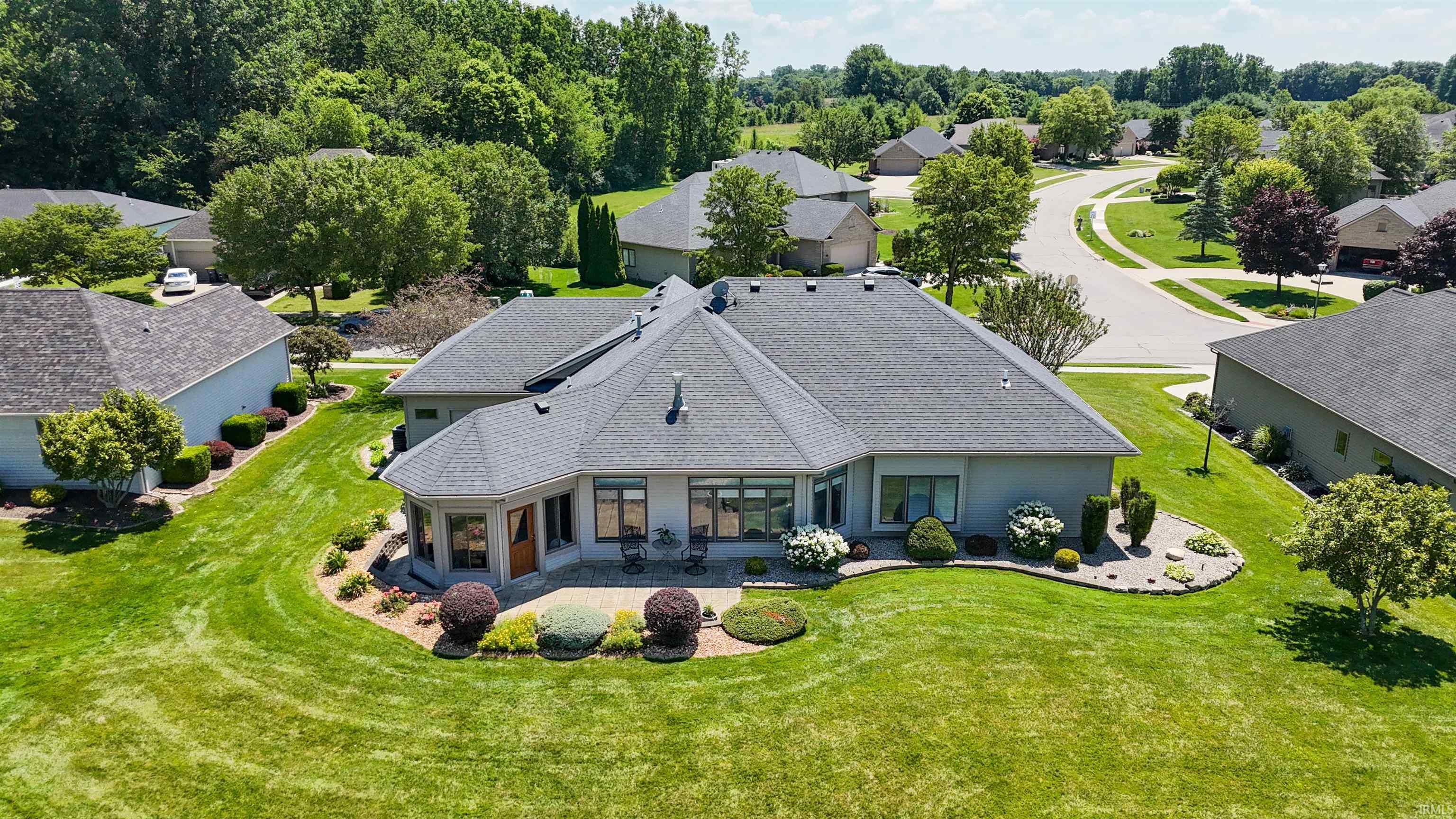 Spacious single-story residence featuring a multi-gabled roofline, light-colored exterior siding, and a rear patio