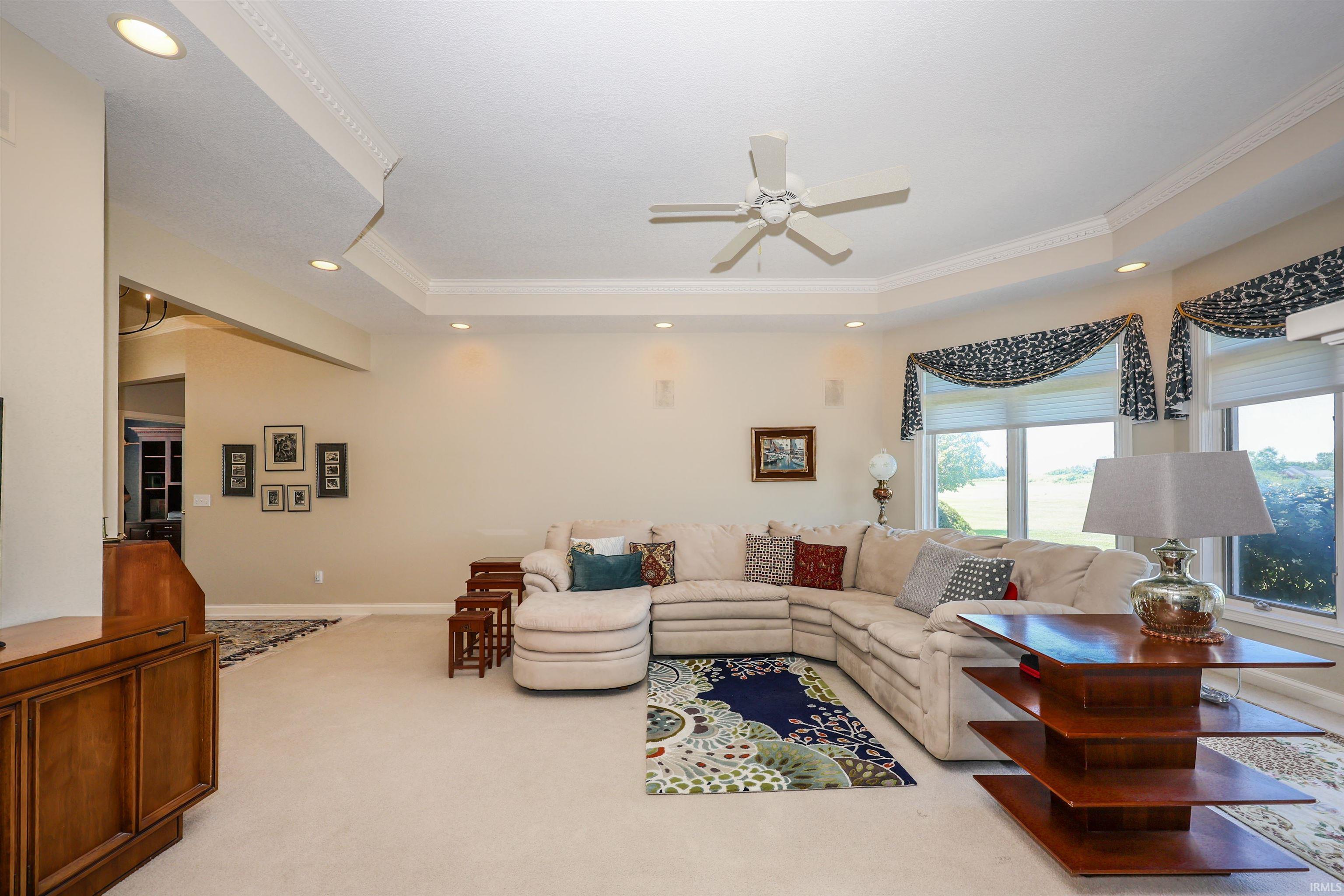 Spacious living area featuring a tray ceiling with recessed lighting and a ceiling fan