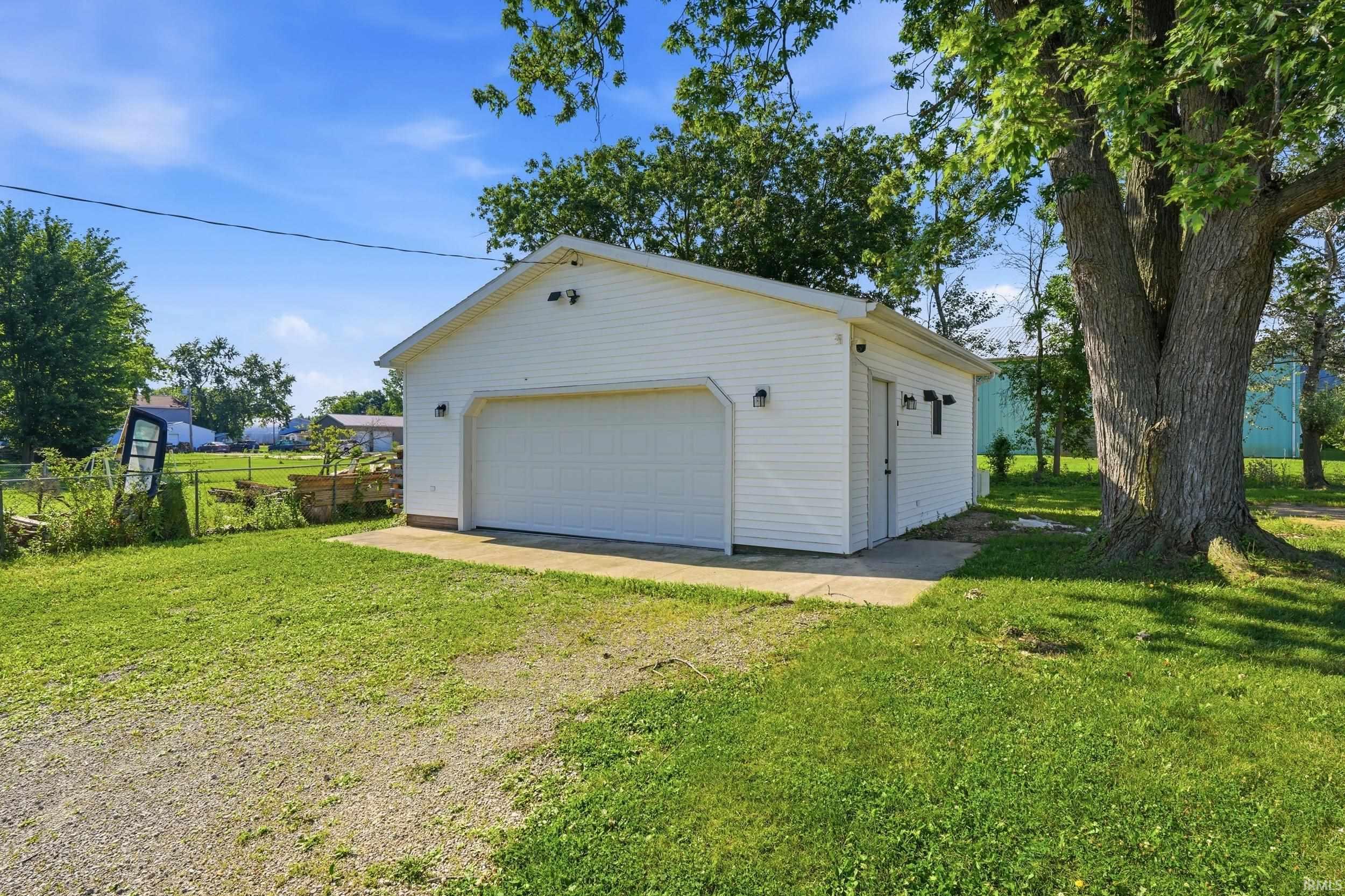Detached garage featuring white vinyl siding, a single overhead door, and concrete apron