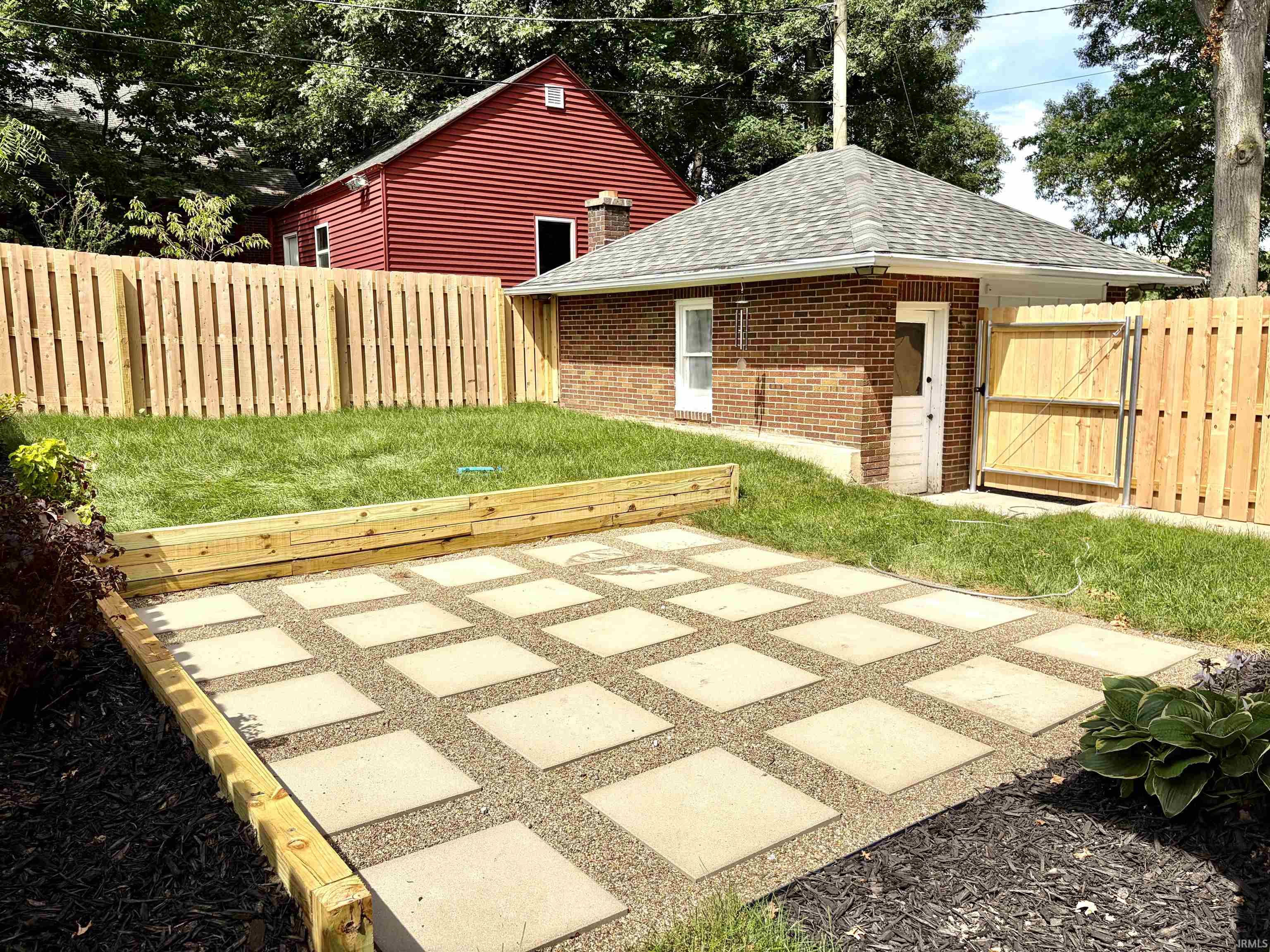 Expansive outdoor living area featuring a stepping stone patio, raised garden beds, and a manicured lawn