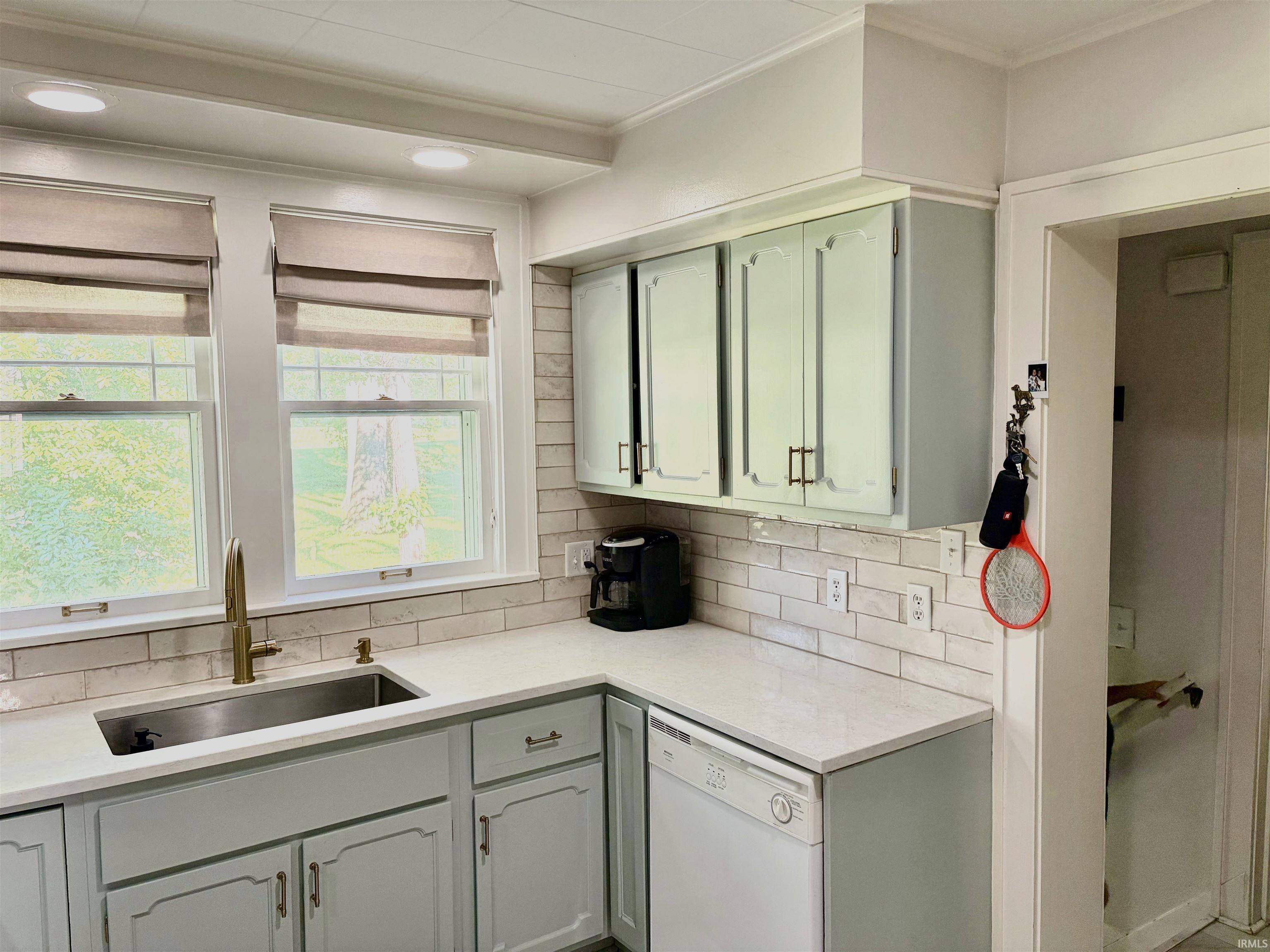 Kitchen featuring white subway tile backsplash, light-colored countertops, and light blue cabinetry