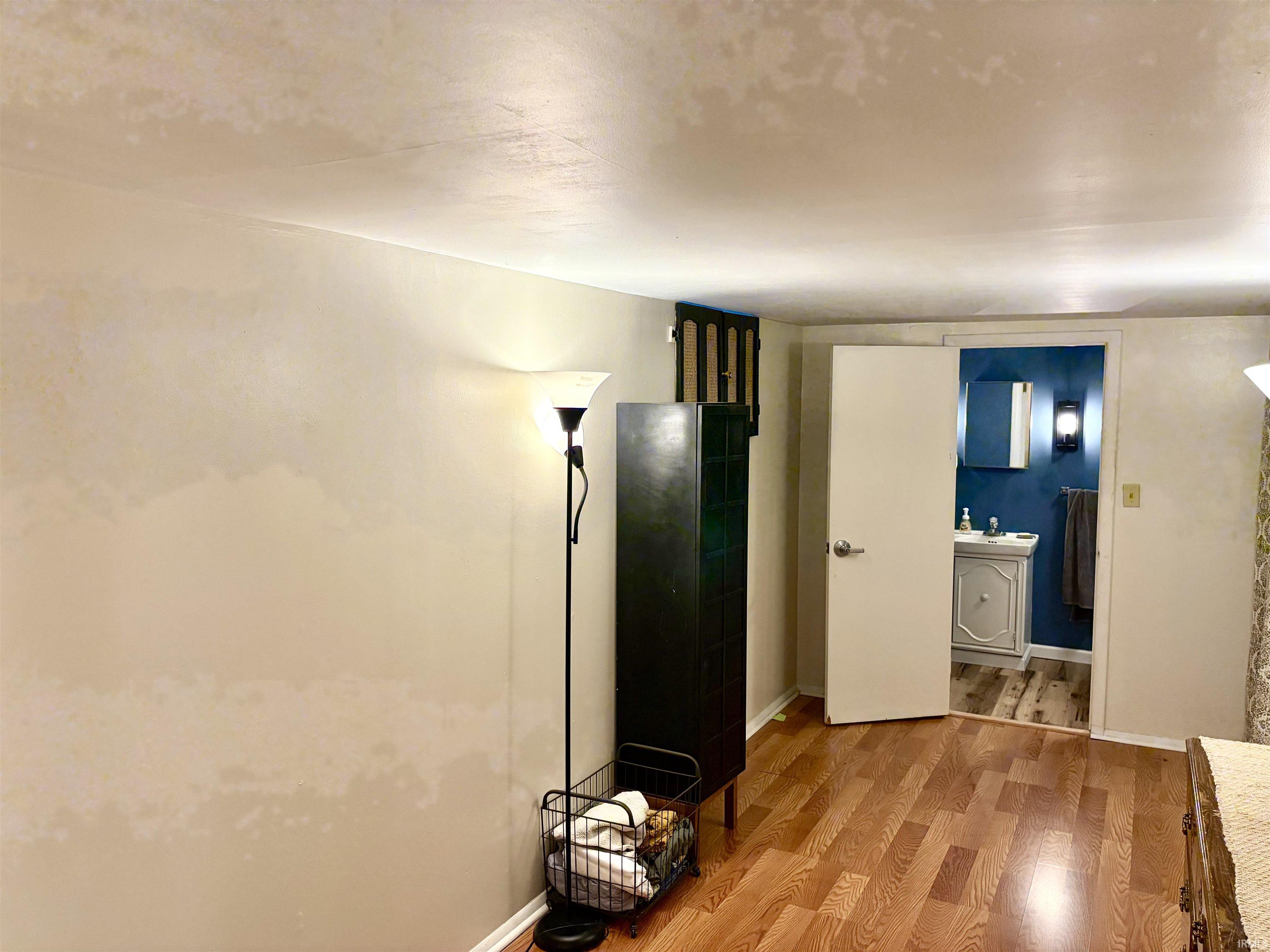 Hardwood-finish flooring leads into a bathroom featuring a dark blue accent wall