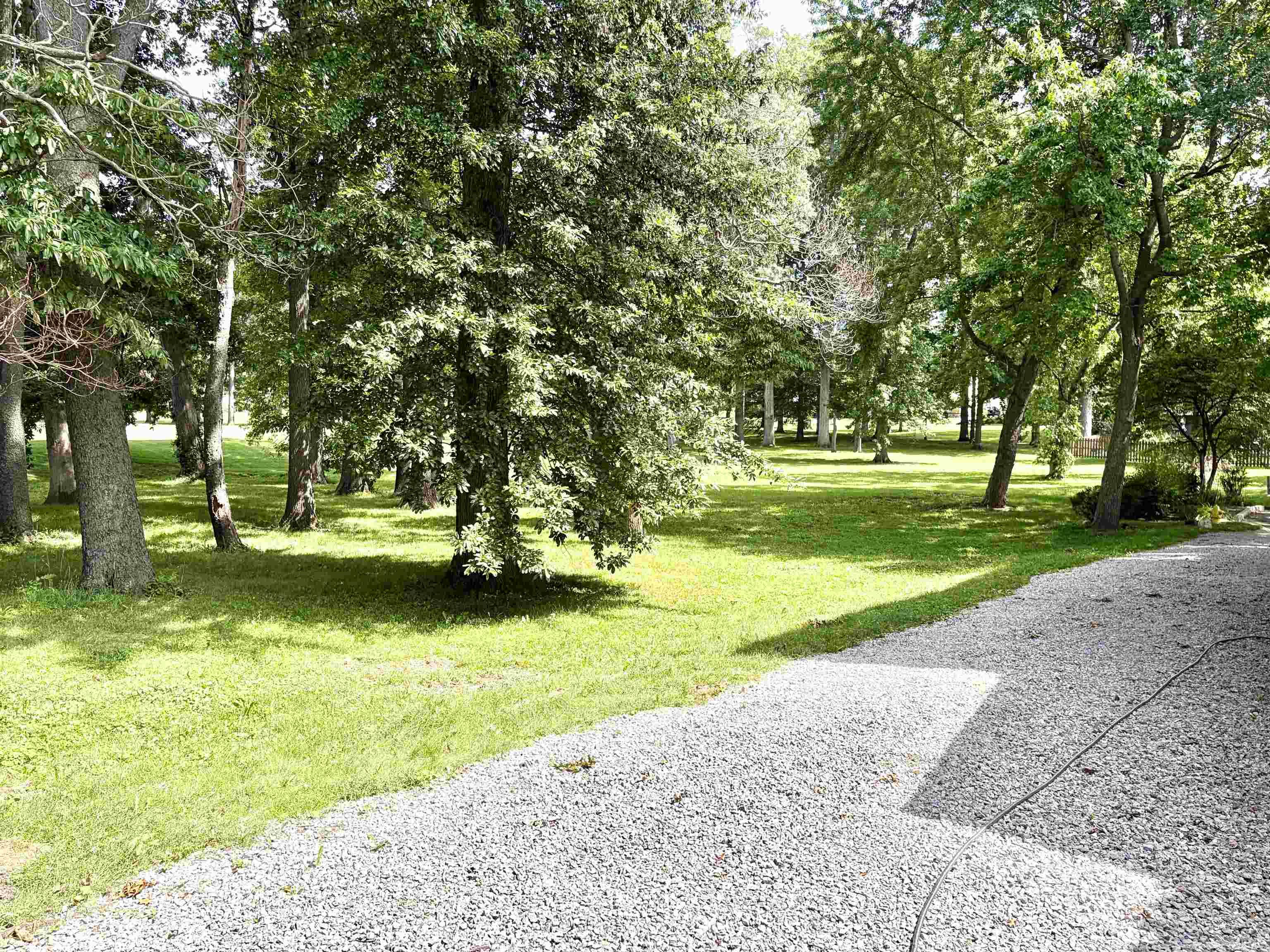 Spacious outdoor area with a gravel surface and expansive green lawn