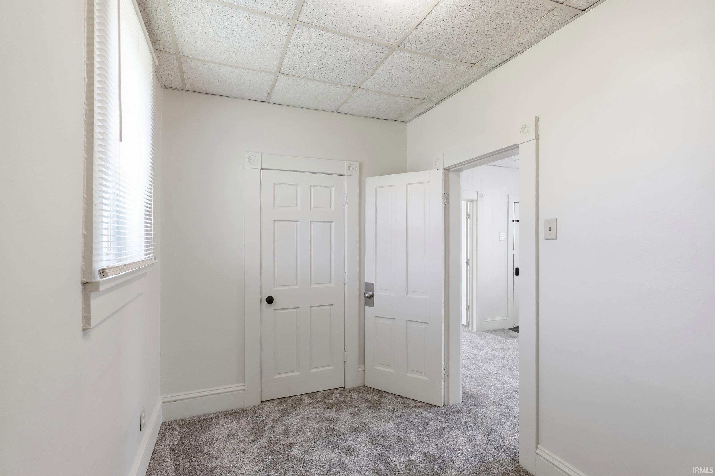 Room featuring light gray carpet flooring, white walls, and a window with blinds
