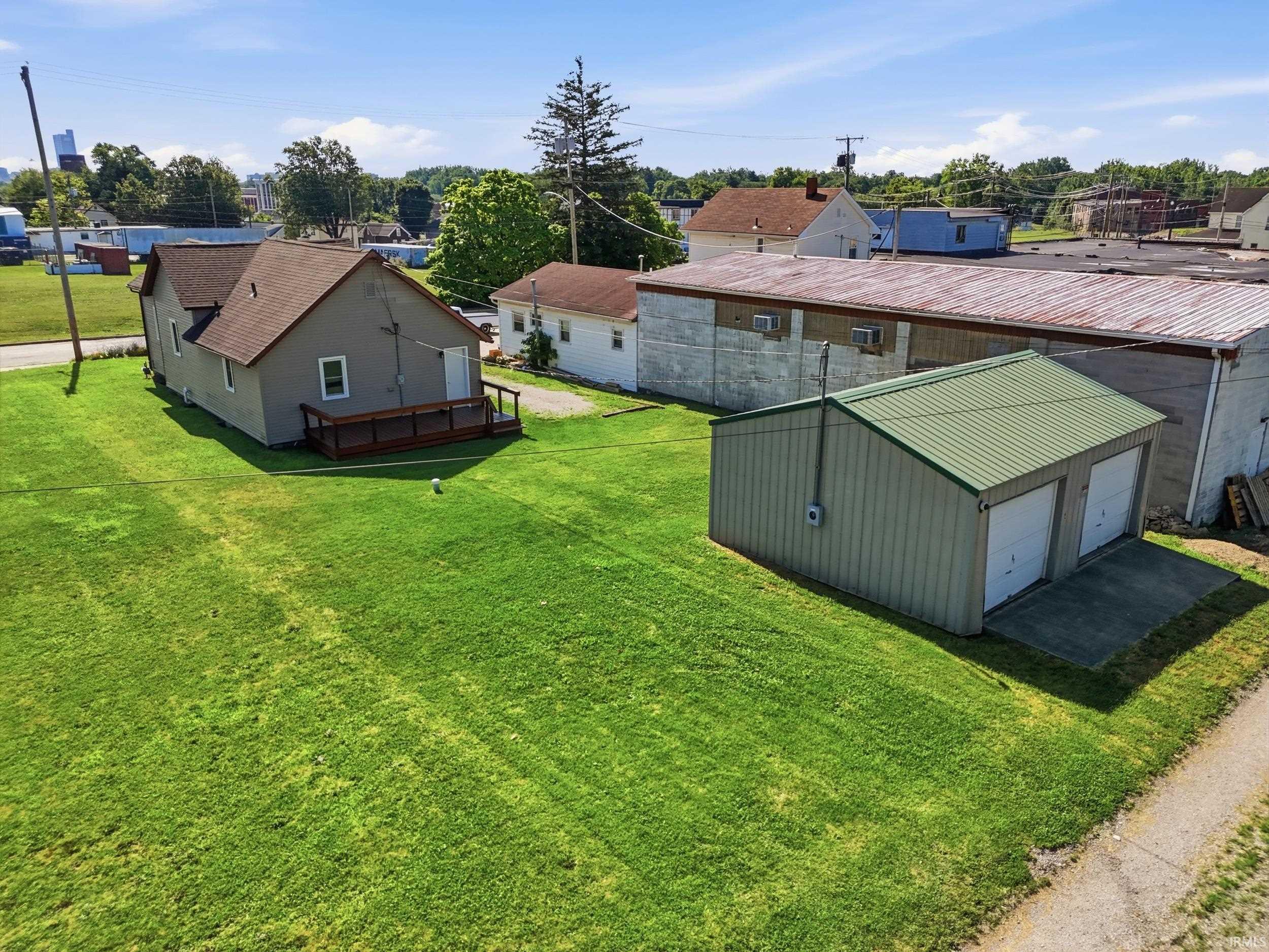 Spacious green lawn with a detached two-car garage featuring a green metal roof and two white garage doors
