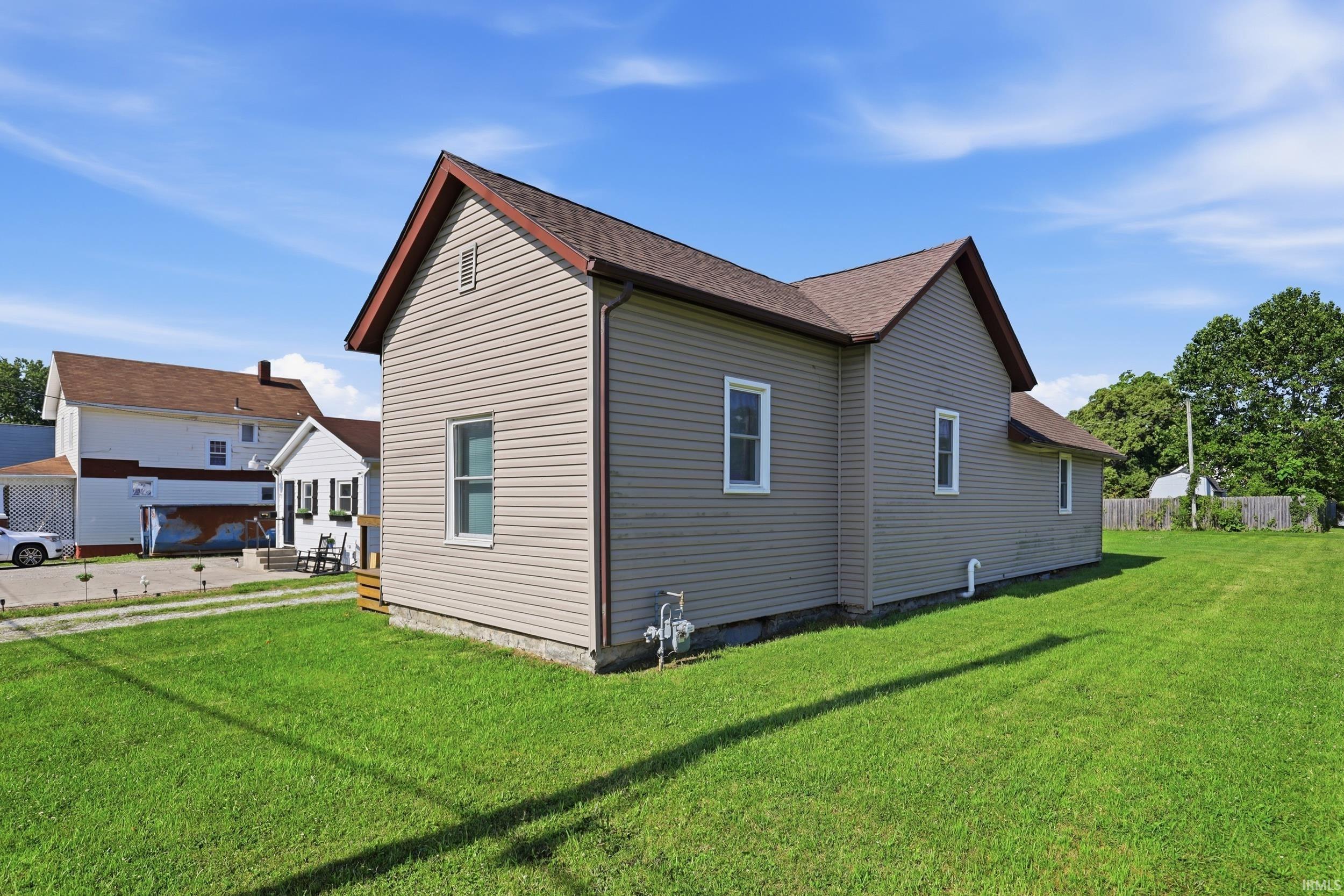 Beige siding exterior with white trim windows and a brown shingle roof
