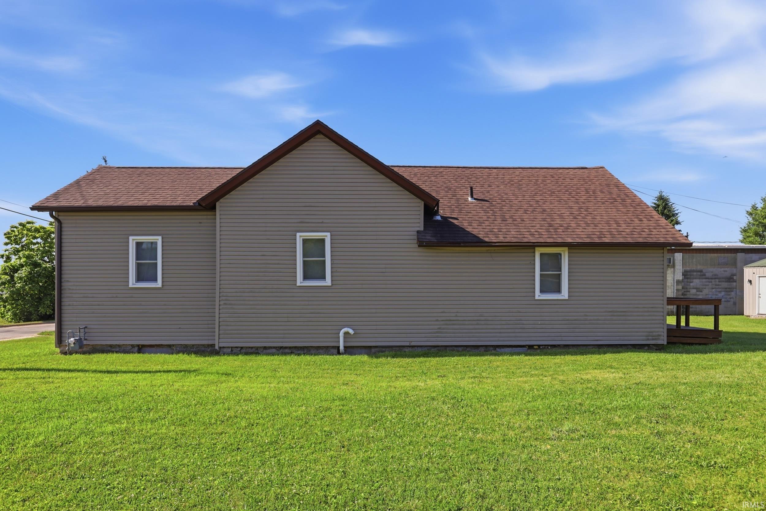 Side exterior showcasing light brown siding and a brown shingle roof