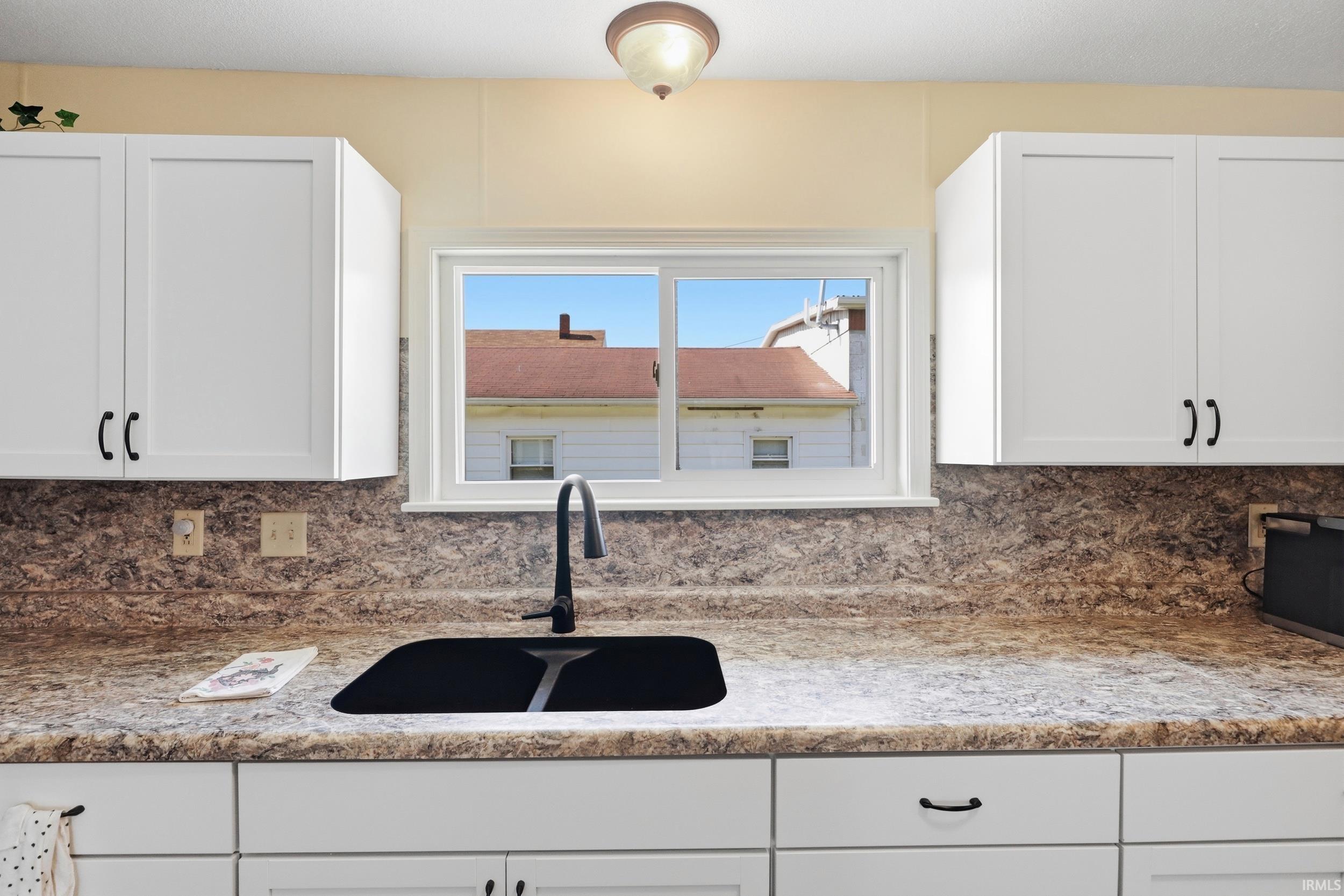 Kitchen featuring a black composite sink with a matte black faucet, set against a patterned countertop