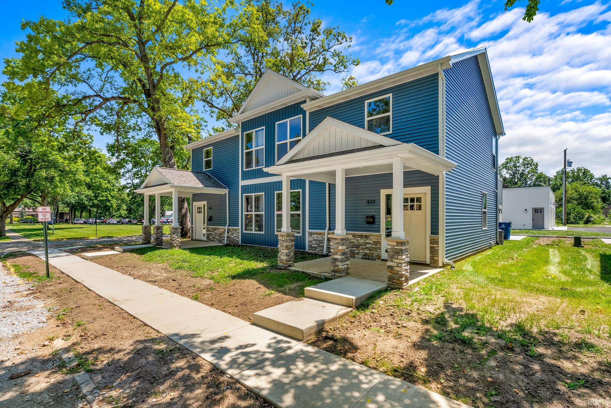 Modern duplex featuring blue horizontal siding, white trim, and stone veneer accents