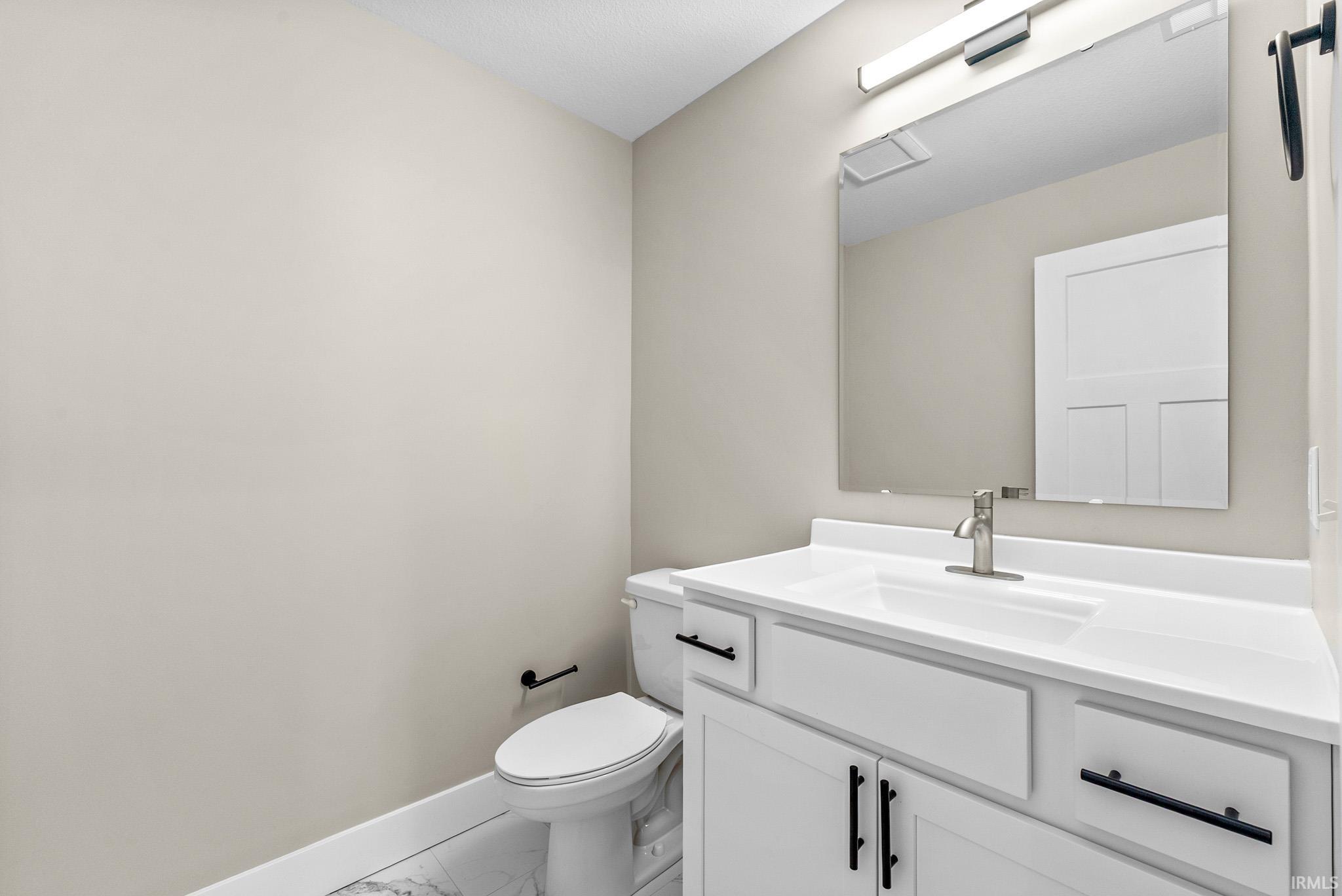 Contemporary bathroom featuring a white vanity with integrated sink, brushed nickel faucet, large wall mirror, and white panel door
