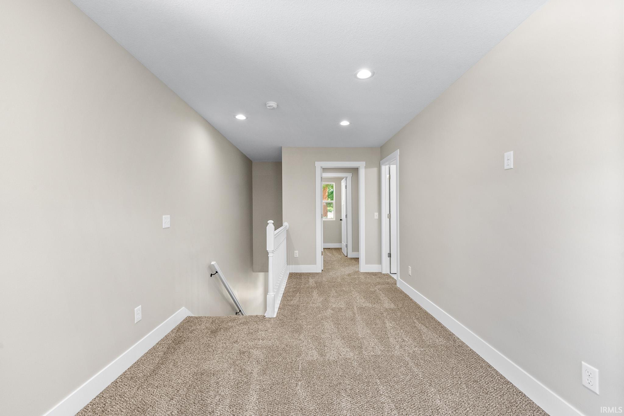 Carpeted loft featuring light neutral wall paint, recessed lighting, white baseboards, and white door trim