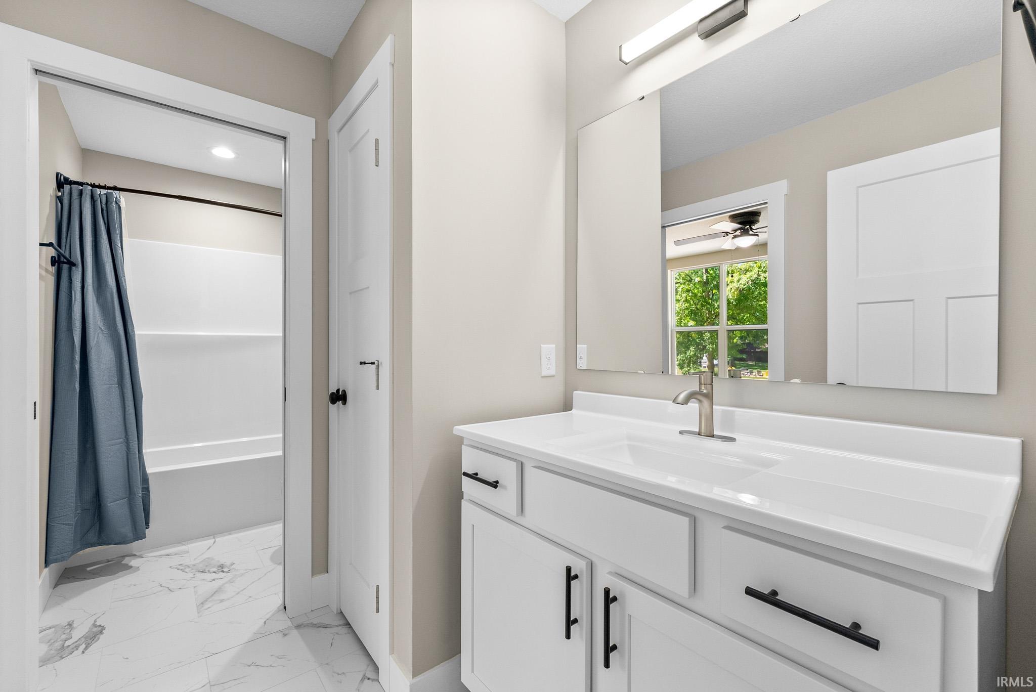 Bathroom vanity featuring a single basin, white countertop, and white cabinetry with black hardware