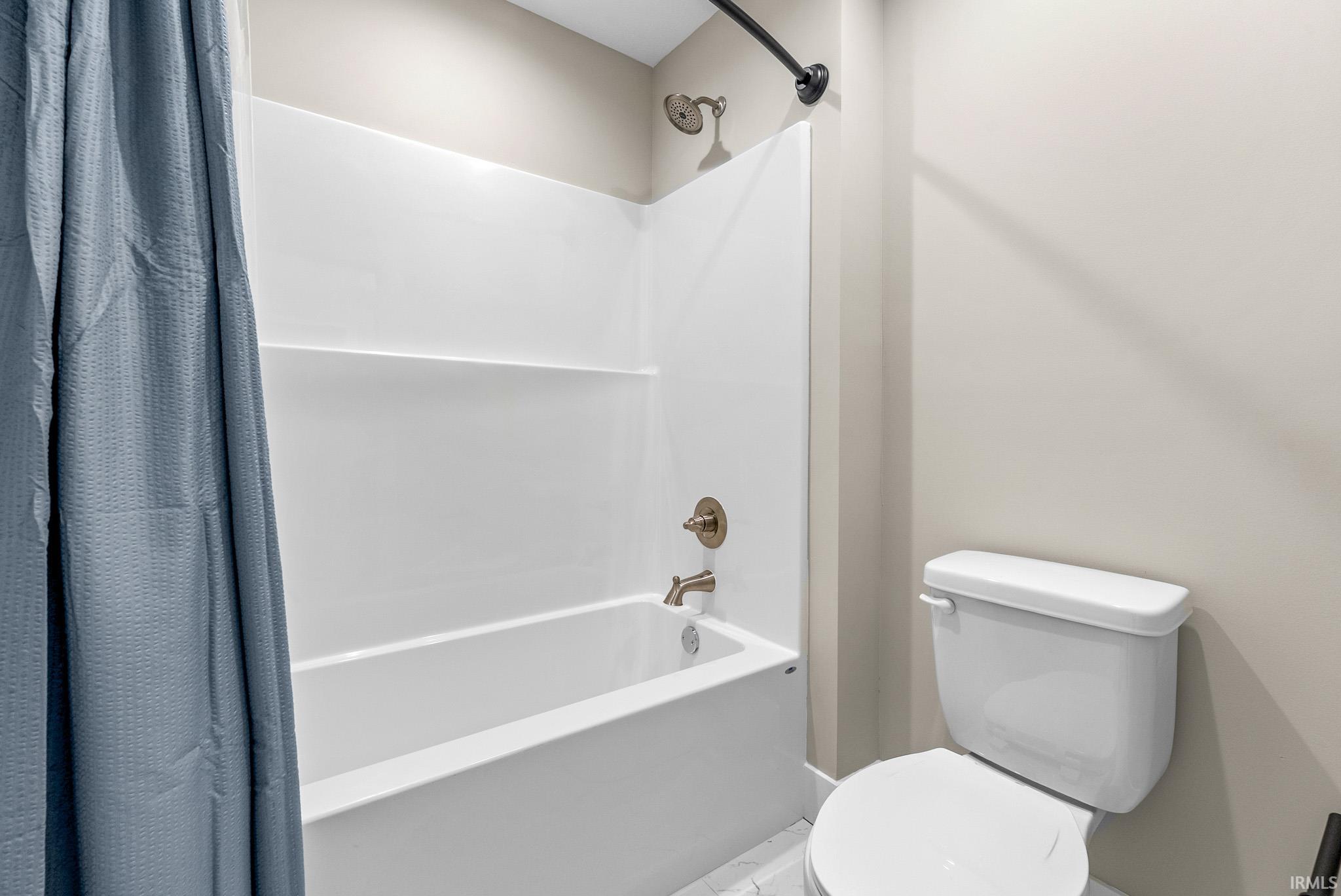 Full bathtub and shower combination with a white surround, brushed nickel fixtures, and a curved shower rod