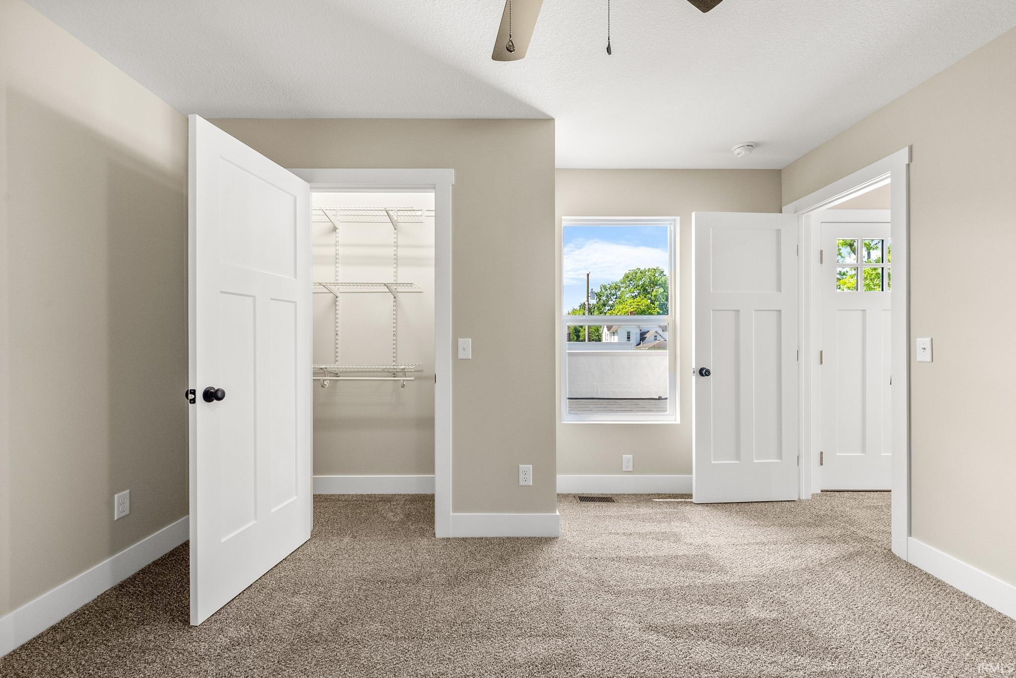 Bedroom featuring neutral-toned carpet, a window, and a ceiling fan