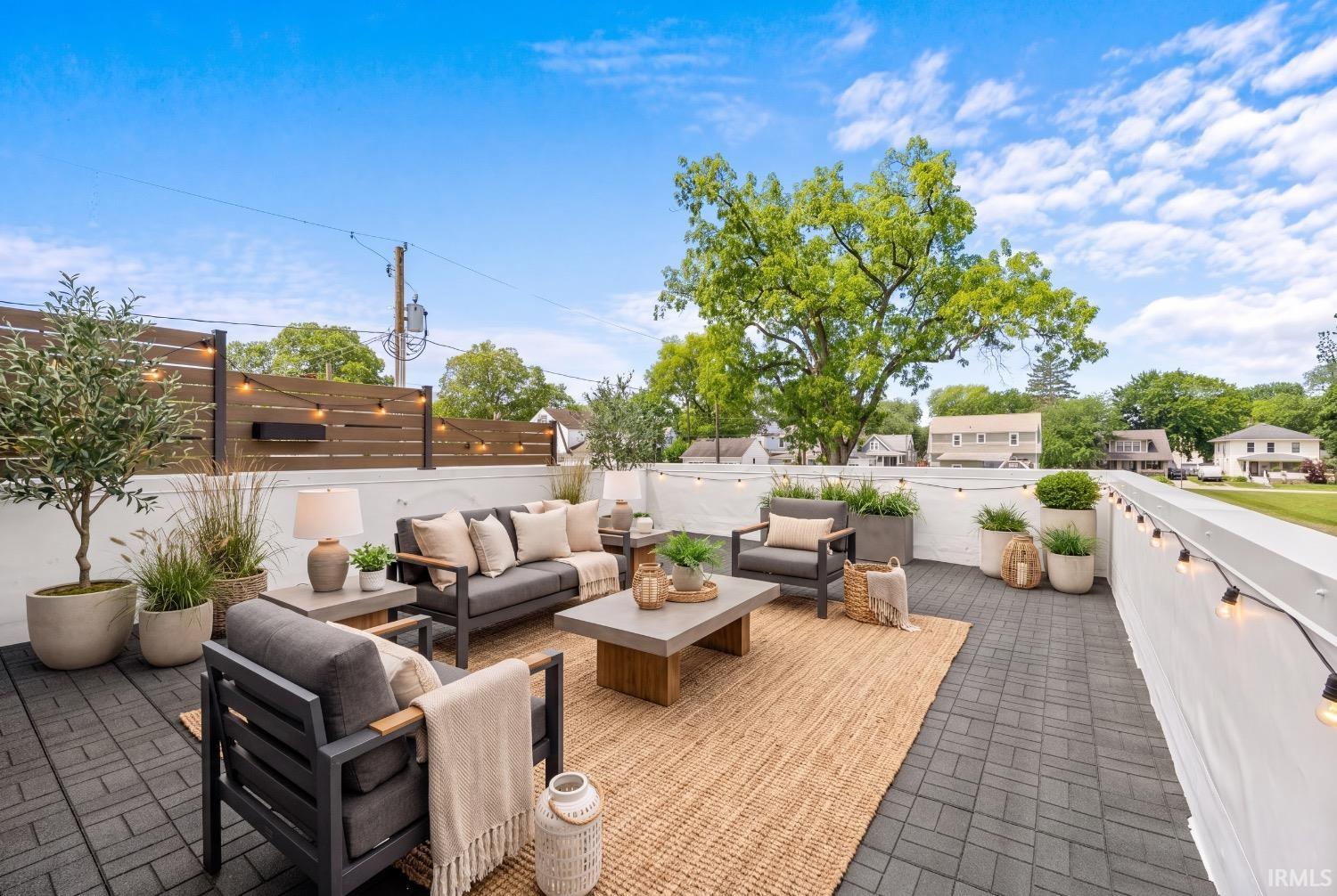 Rooftop deck featuring paver flooring, a slatted privacy fence, perimeter string lighting, and an expansive open-air setting