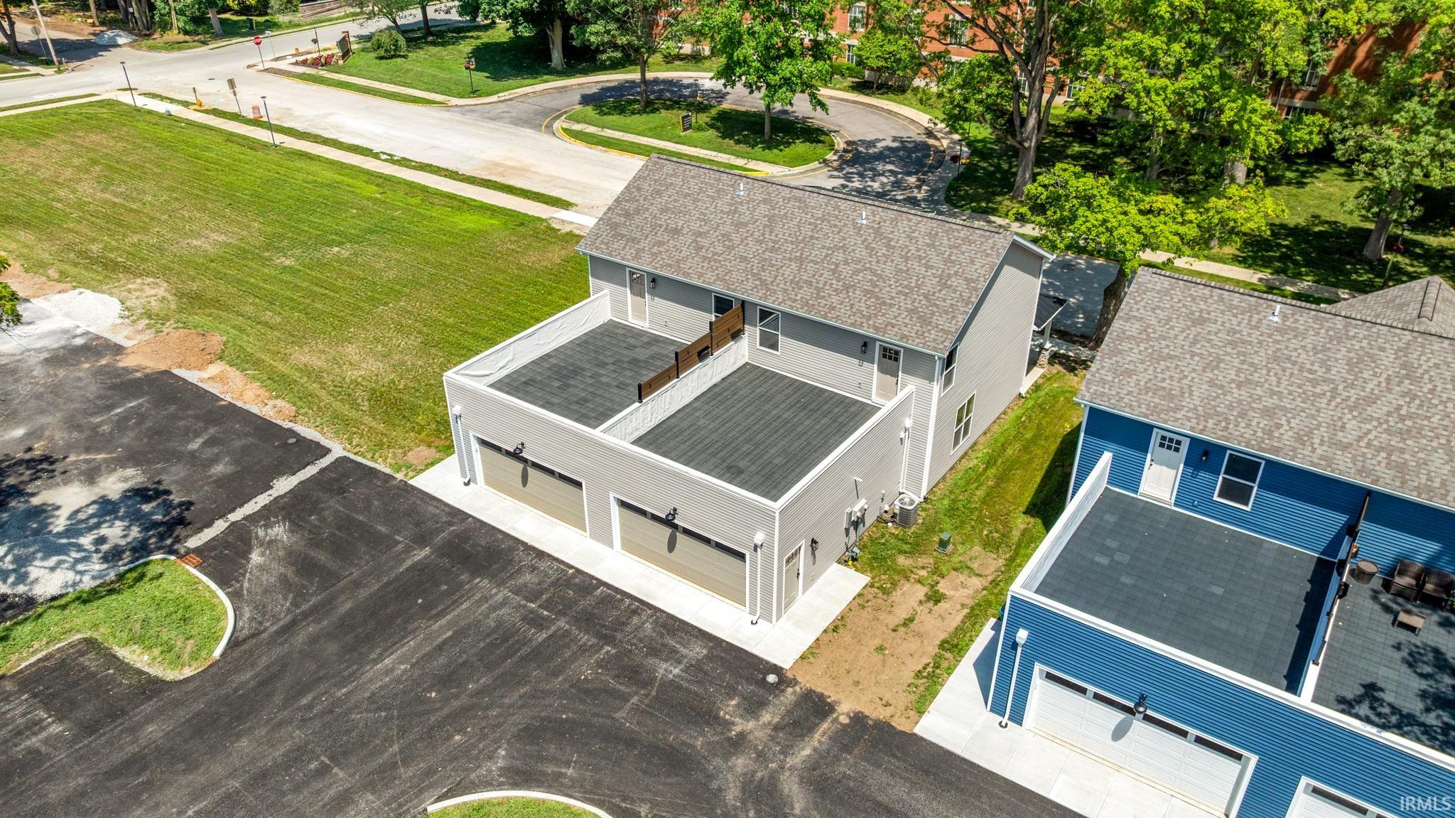 Two-story gray siding residence featuring a two-car garage, a second-story balcony, and a shingle roof