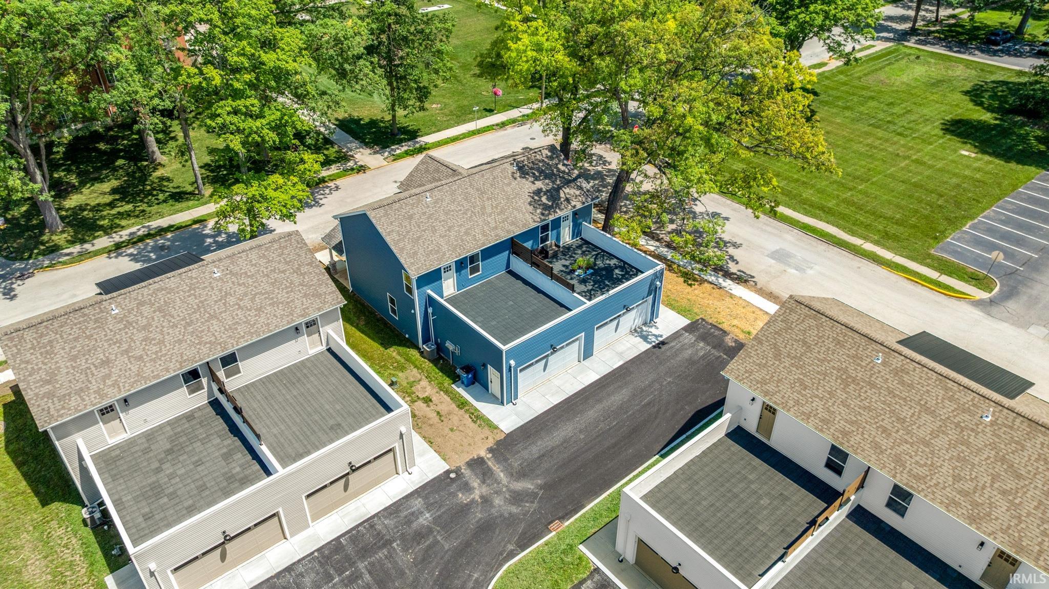 Aerial perspective showcasing three multi-unit structures with asphalt driveways