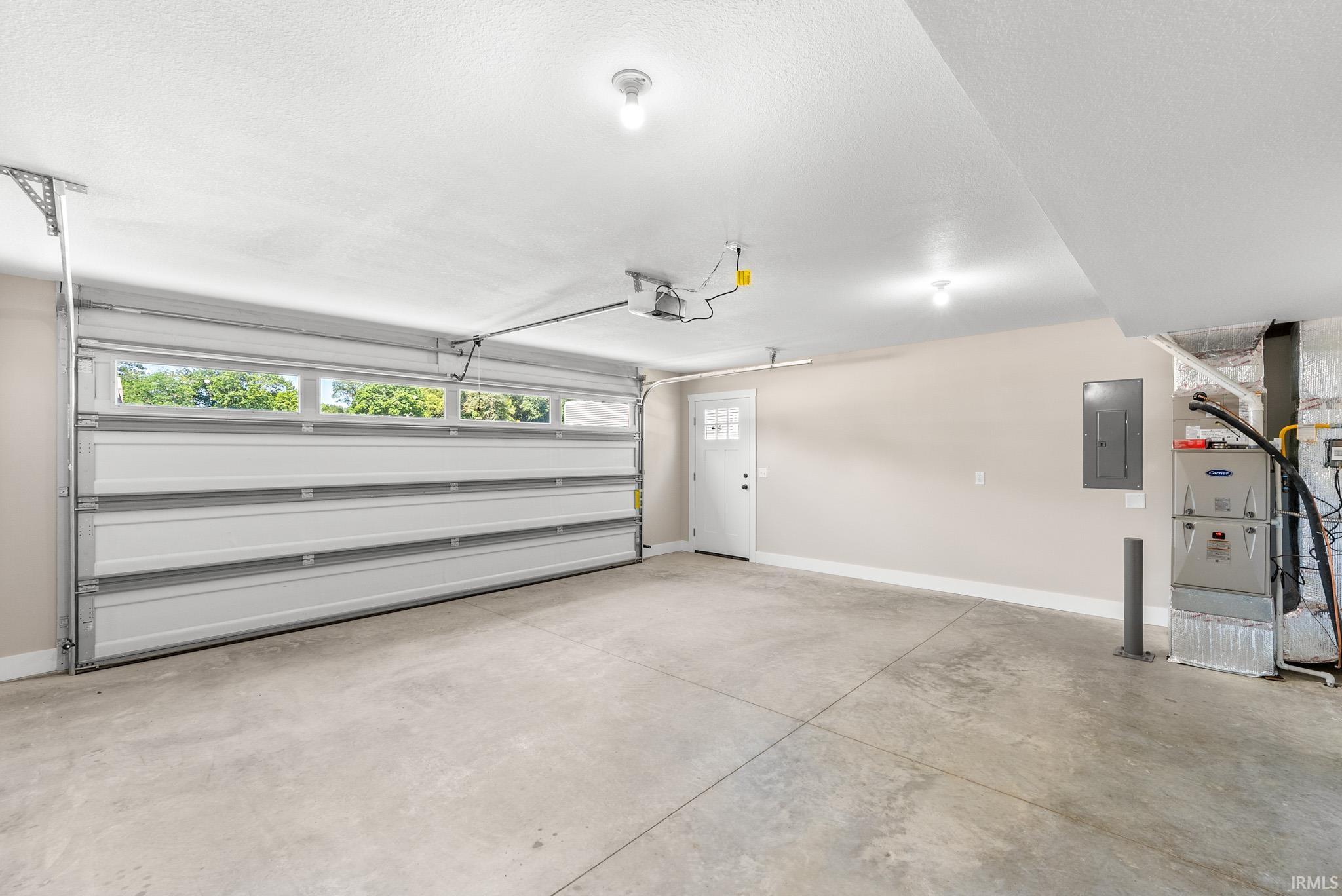 Spacious concrete-floored garage featuring a white overhead door with upper-level windows