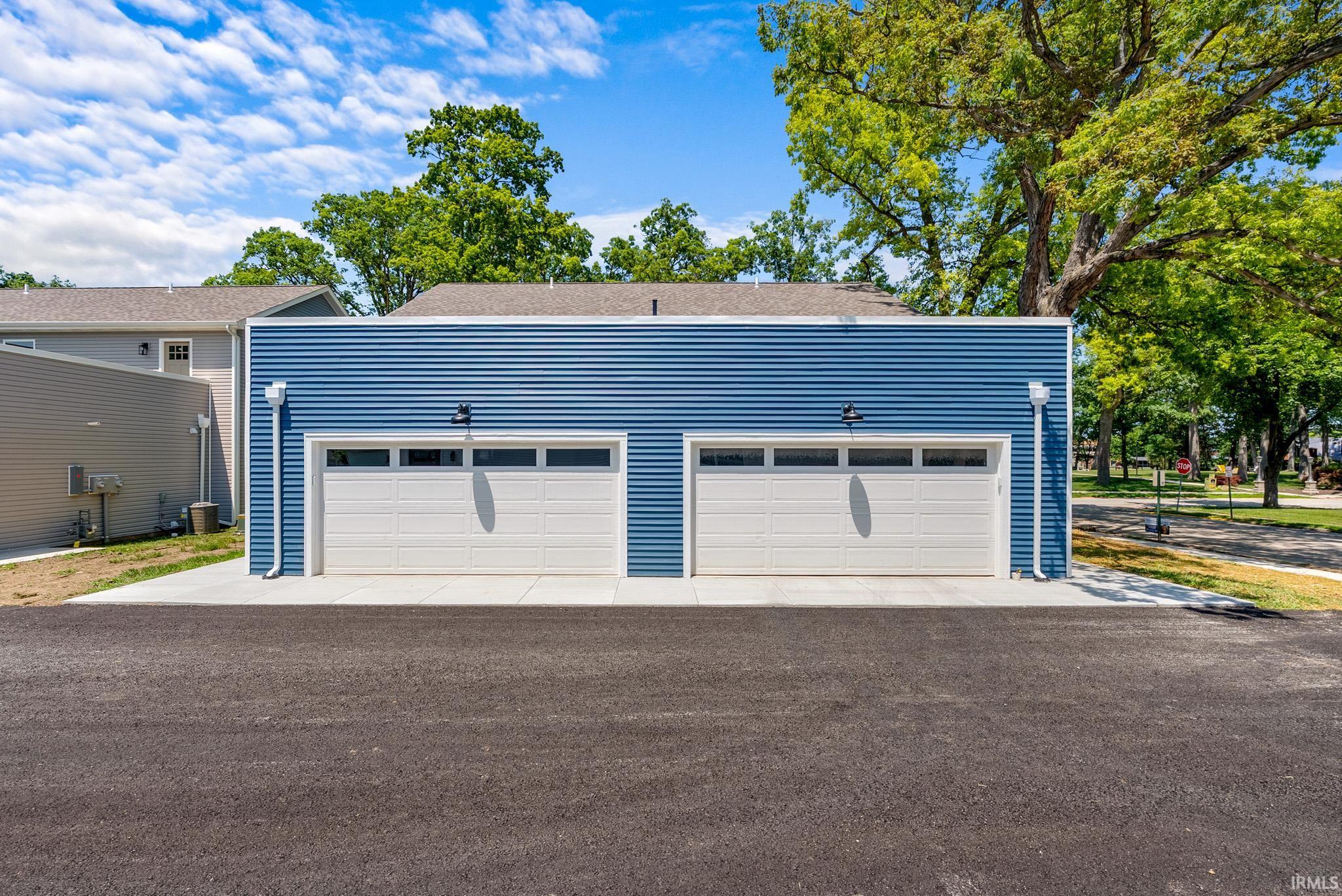 Two-car garage featuring blue horizontal siding, white garage doors with upper window panels, and concrete apron