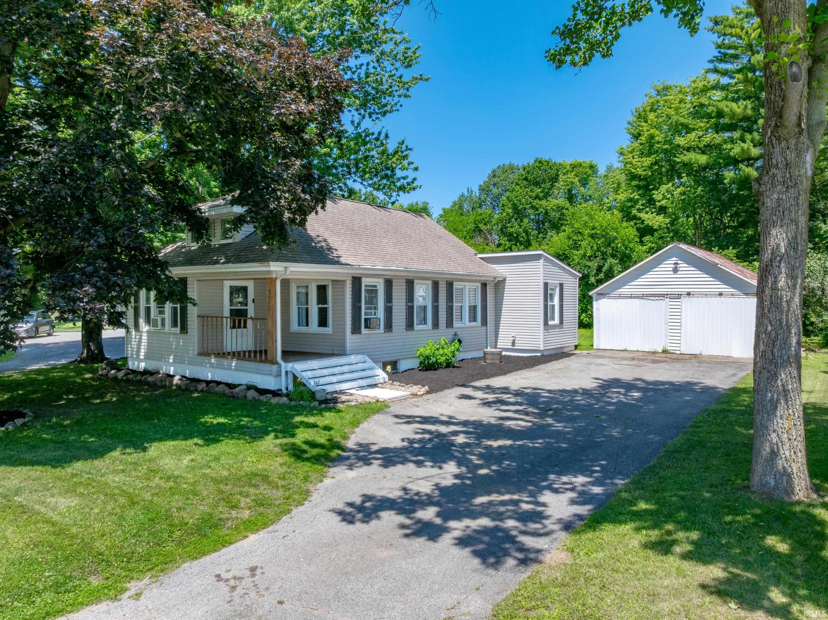 Light gray siding exterior with dark shutters, a covered front porch, and a dormer